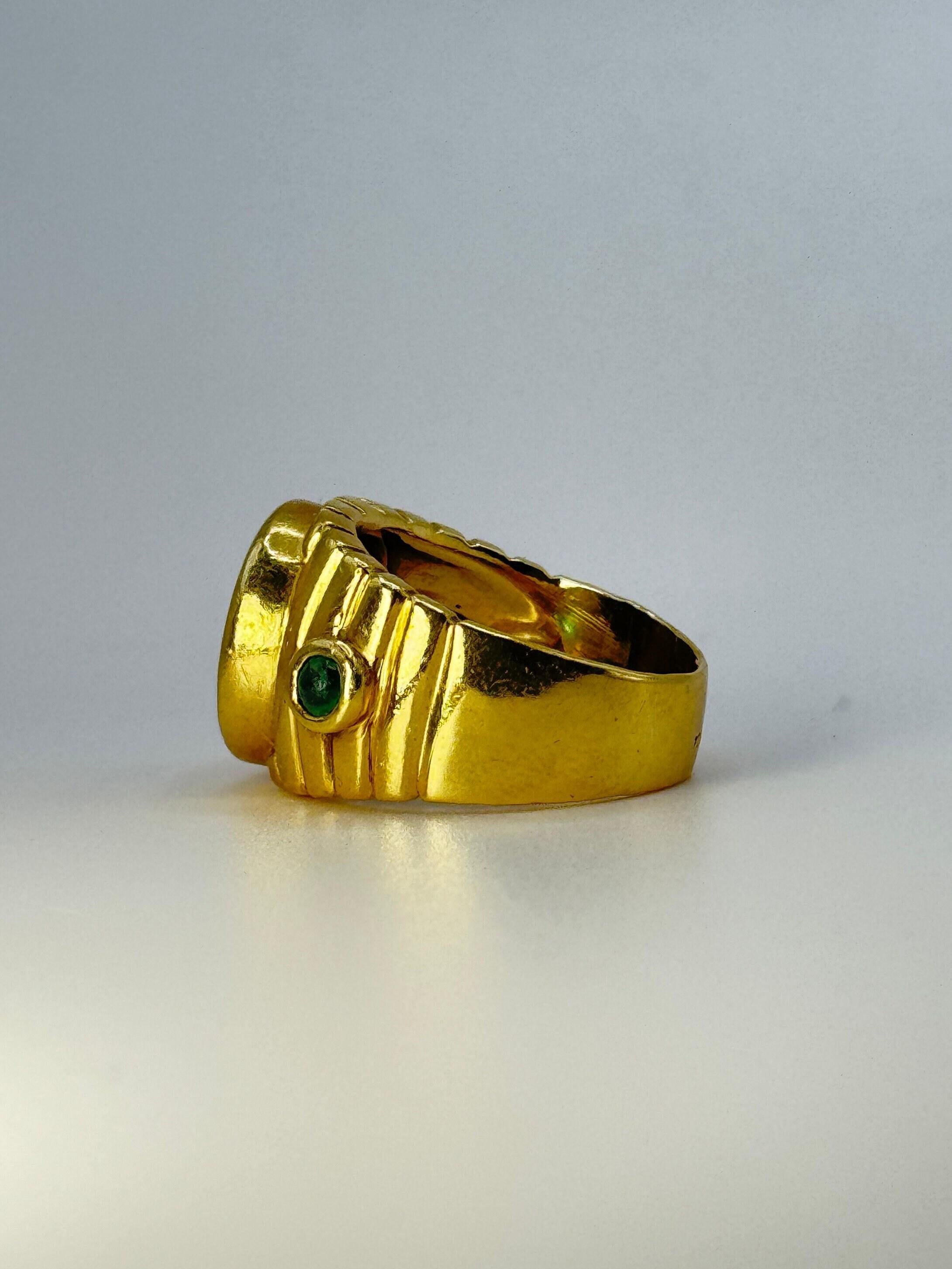 Werten Sie Ihre Sammlung mit diesem edlen Siegelring im Vintage-Stil auf, der eine echte römische Münze zeigt. Dieser 11,5 Gramm schwere Ring aus prächtigem 18-karätigem Gold, flankiert von zwei schimmernden Cabochon-Smaragden, ist eine