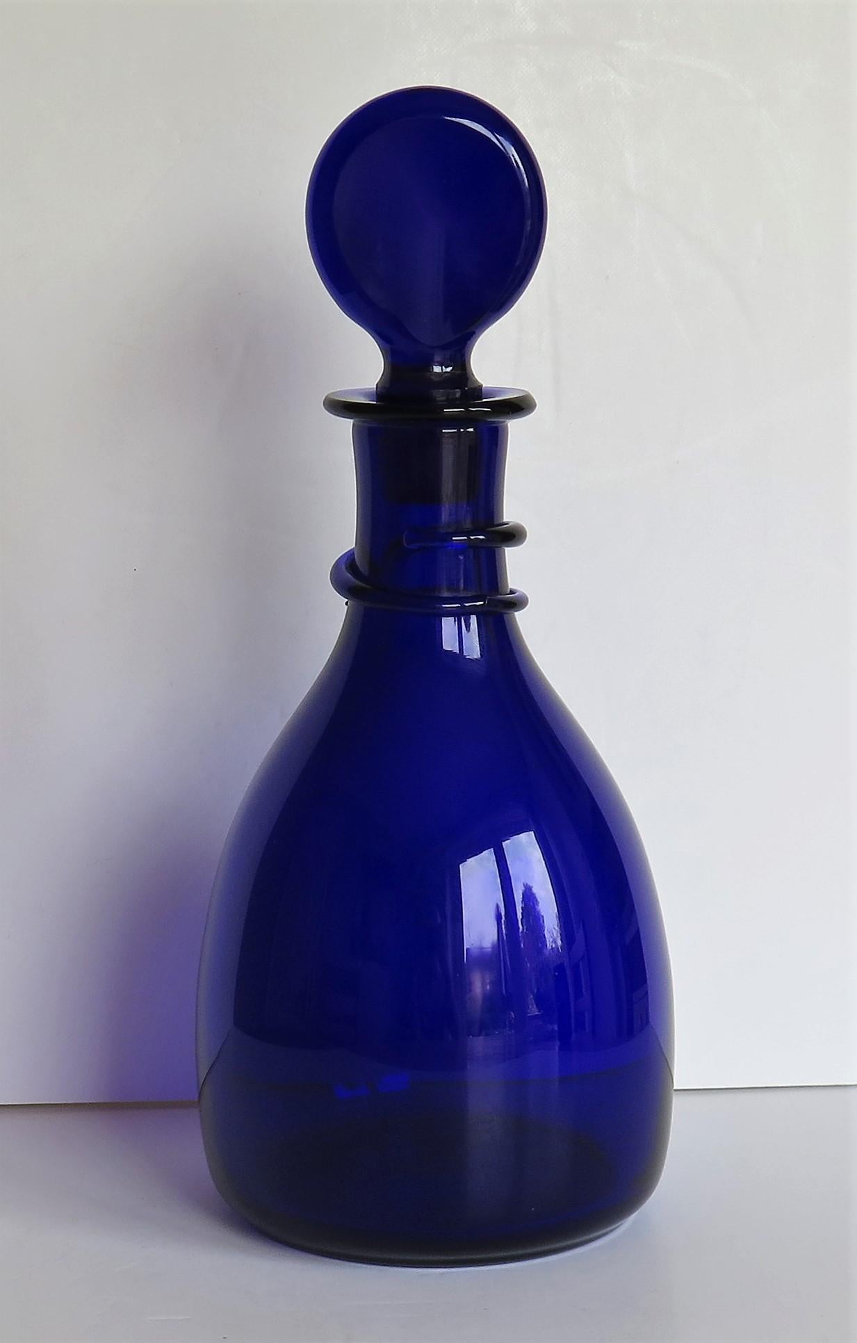 This is a very good hand blown bristol blue glass decanter having an unusual snake trailed neck ring and complete with its original lozenge stopper, made of heavy blue lead glass, circa 1790. There is a rough pontil mark to the base from the hand