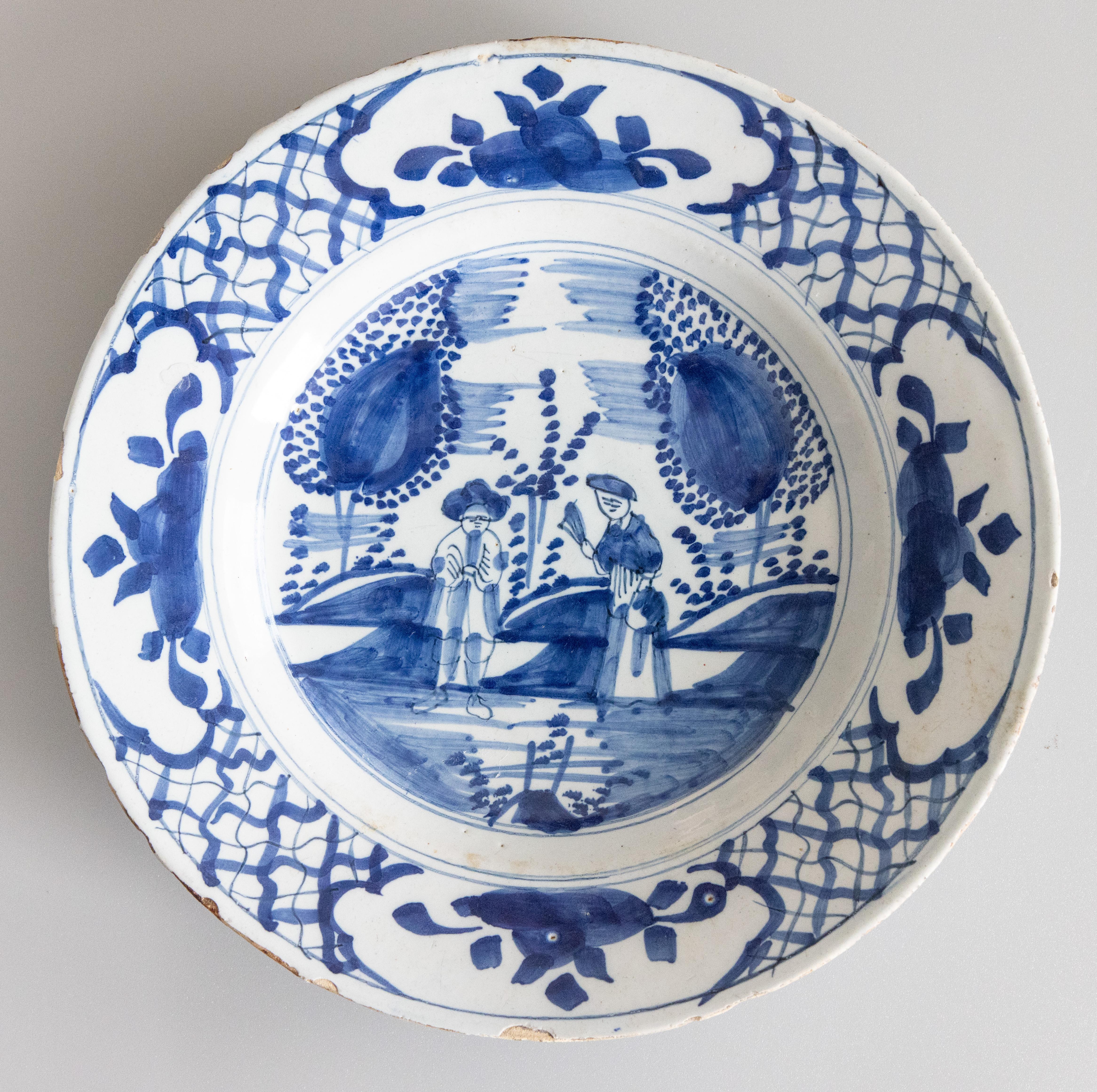 Paire d'assiettes en chinoiserie de Delft du XVIIIe siècle, remarquablement conservées, présentant de charmants personnages encadrés par des arbres, des scènes de jardin et une jolie bordure peinte. 