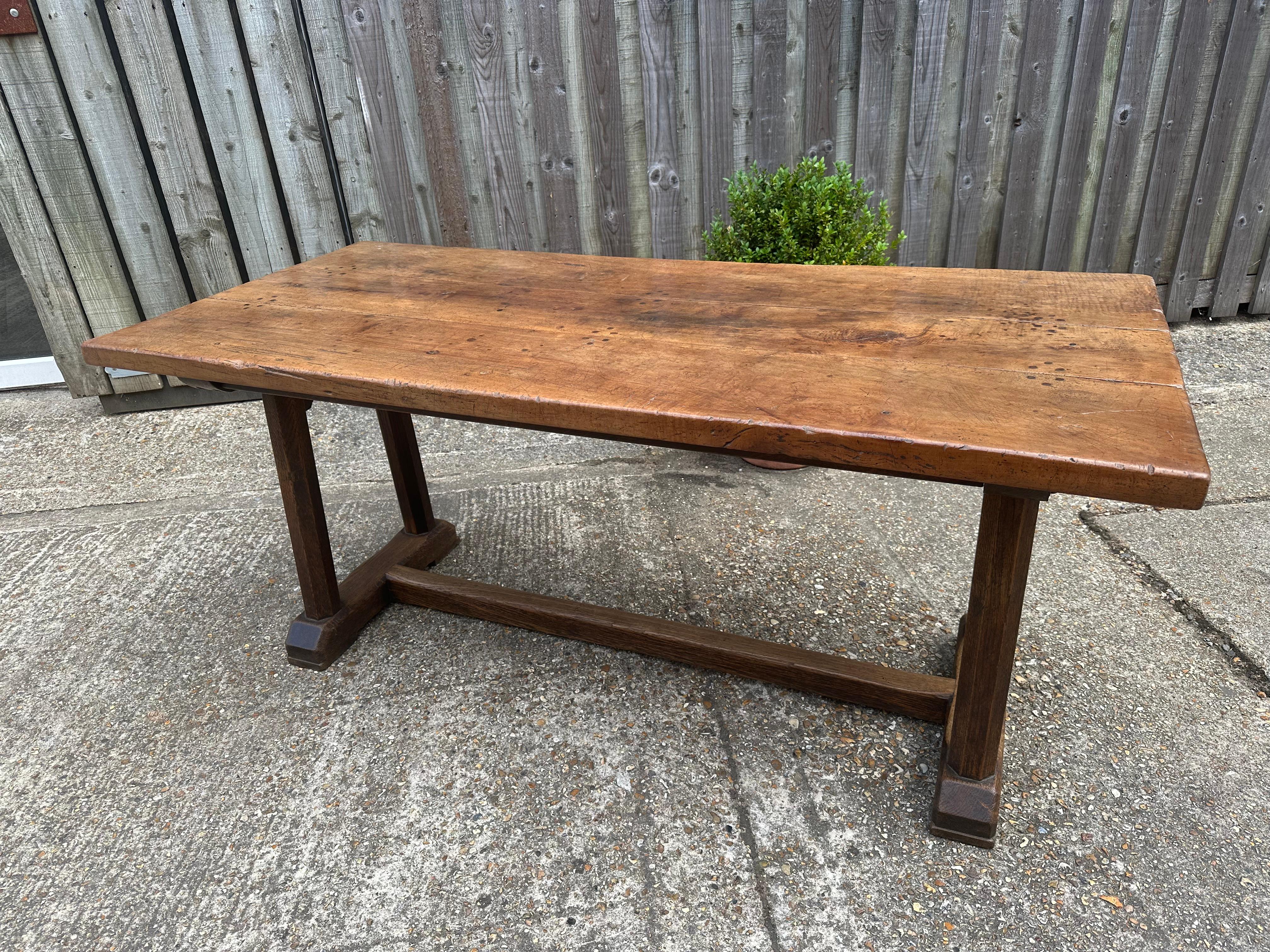 Esta exquisita mesa de comedor, fabricada en una rara madera de peral del siglo XVIII, presenta un diseño extraordinario con una llamativa base de caballete de dos pilares y un elegante travesaño central para mayor estabilidad.  El tablero es una