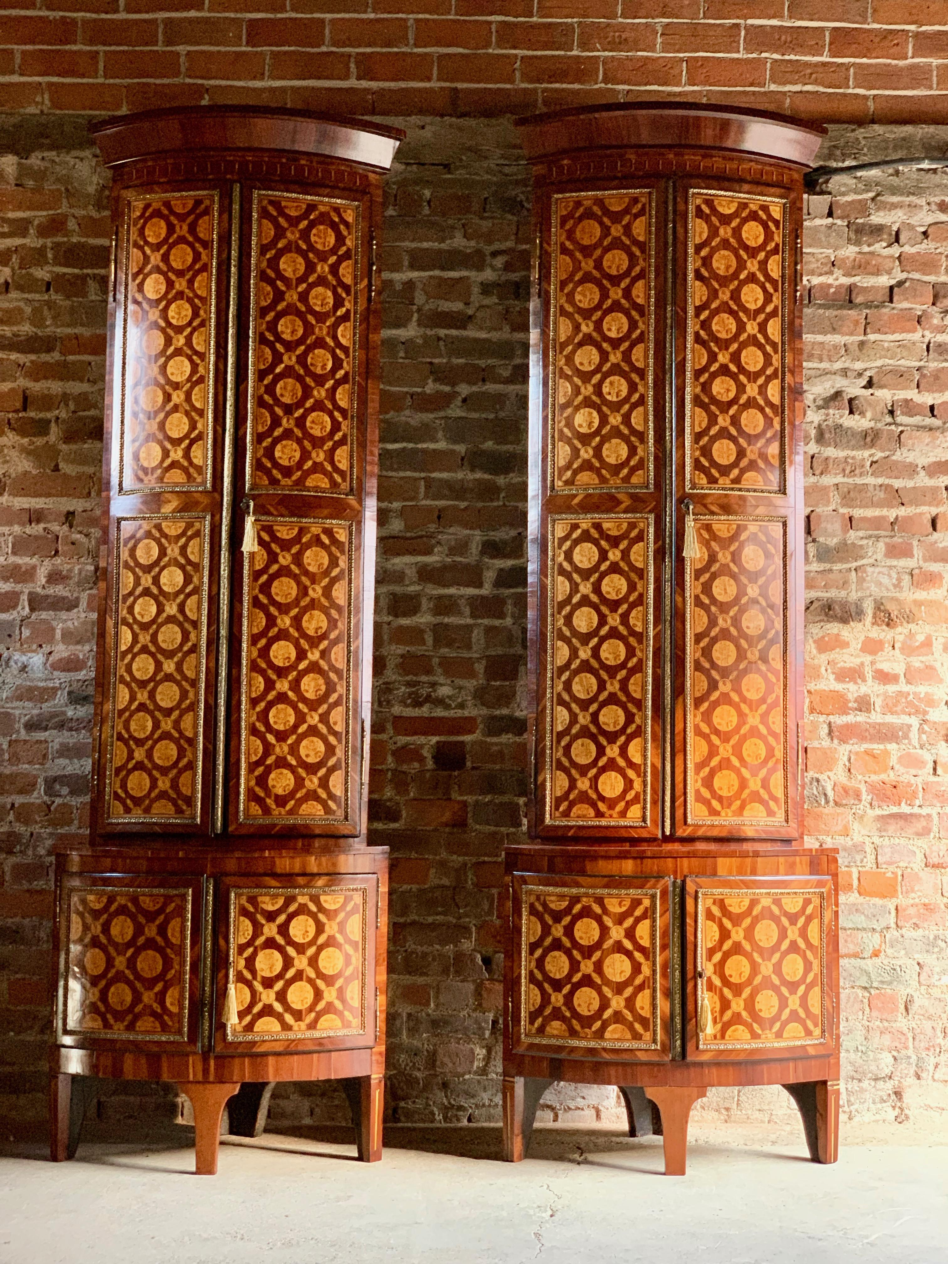 A very rare and unique pair of late 18th century Dutch bow fronted floor standing corner cupboards, circa 1780, the protruding cornice over a pair of brass bound panelled doors profusely inlaid with marquetry of lattice design and flowers, enclosing
