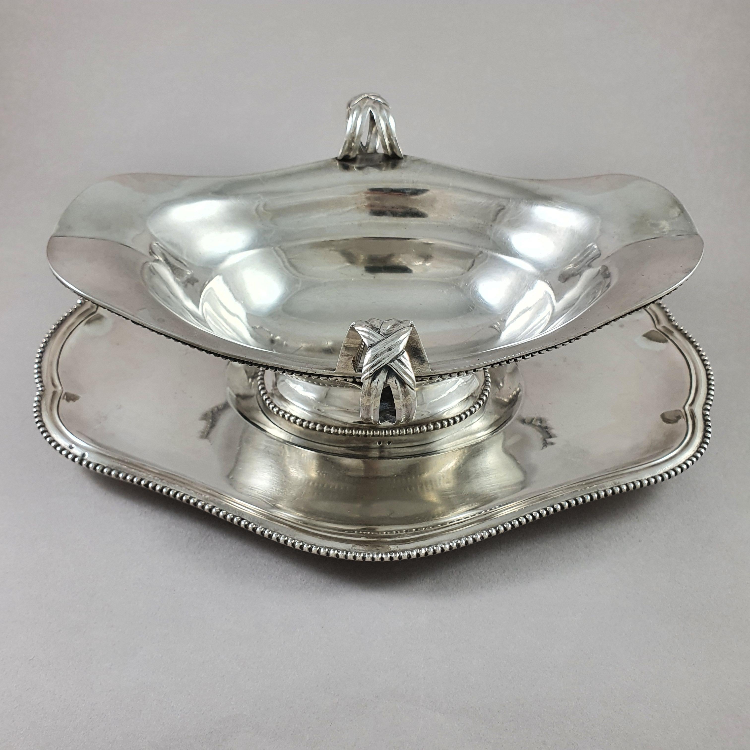 Rare sauceboat and its frame in sterling silver from the 18th century 

Oval in shape with two pouring spouts, decorated with ribboned knots and finished with foliage, the borders with rows of pearls 

Hallmarked A crowned for Paris between 1783