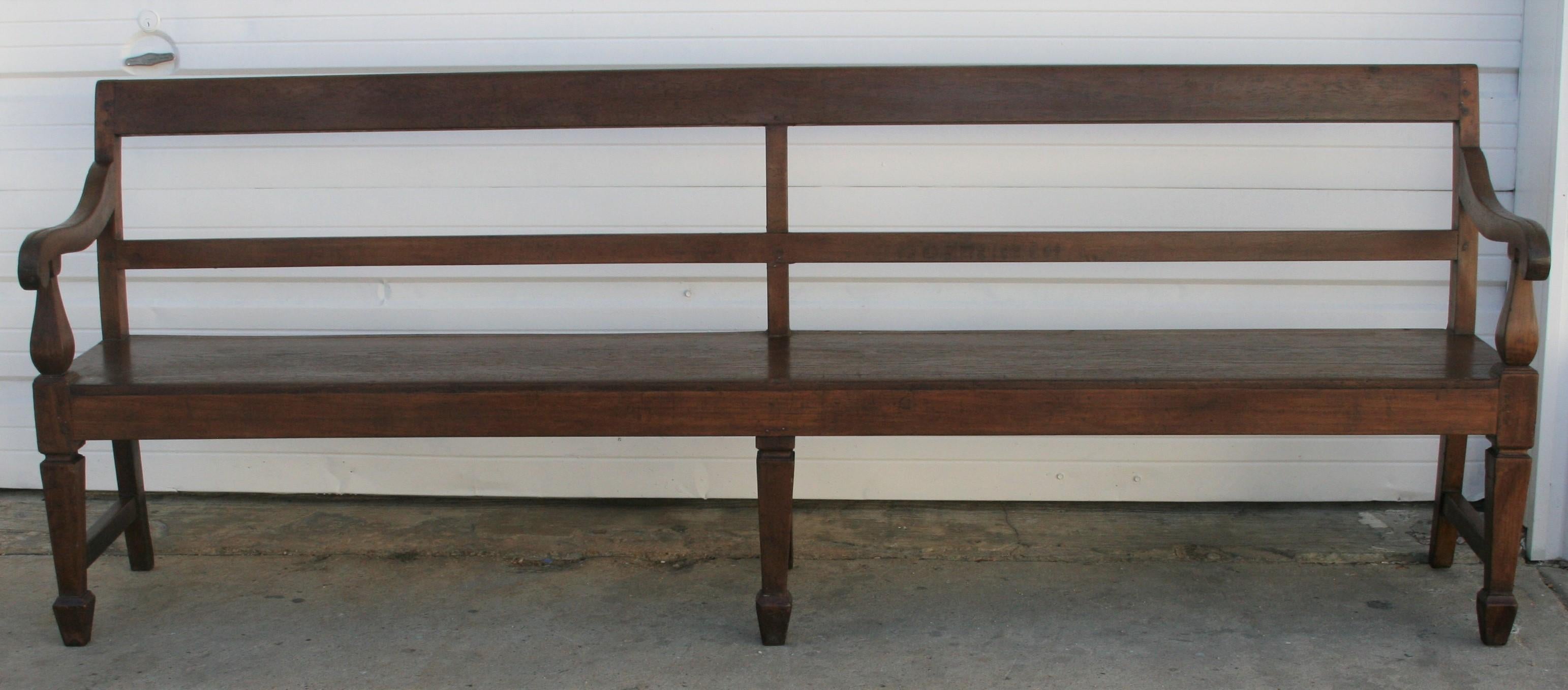 The first thing that catches the eyes when you look at this bench is the mellowing wood patina of the aging teak wood. It is a large bench with a seat almost made from one plank of wood with hand rests on either side with plain back and supported on