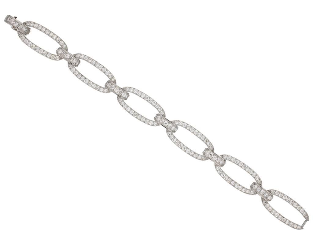 Diamond bracelet by Georges Fouquet, French, circa 1920. A platinum bracelet composed of six oval links joined by six curved bar shaped links including an integrated clasp, set with one hundred seventy four round old cut diamonds in millegrain bead