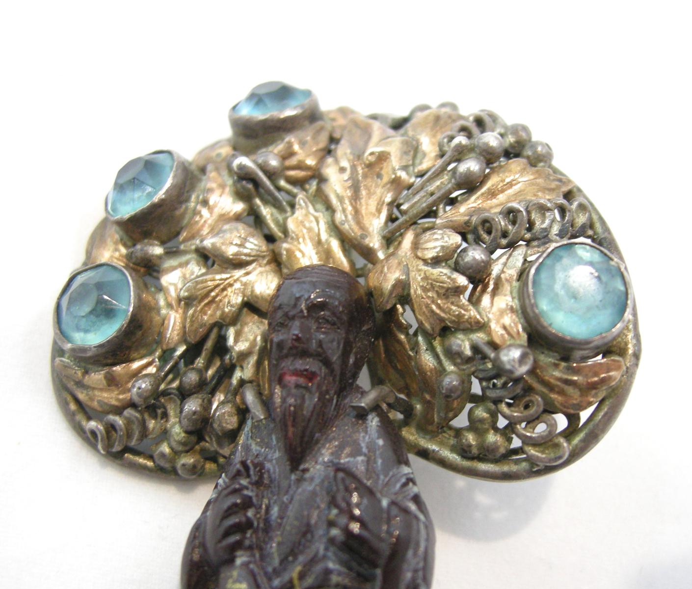 This is a rare 1930s vintage Hobe brooch created with an Asian man in a dark, heavily carved coral. The large golden halo has aqua color crystals in sterling silver with a gold wash.  This Hobe piece of art is very highly collectible and has been in
