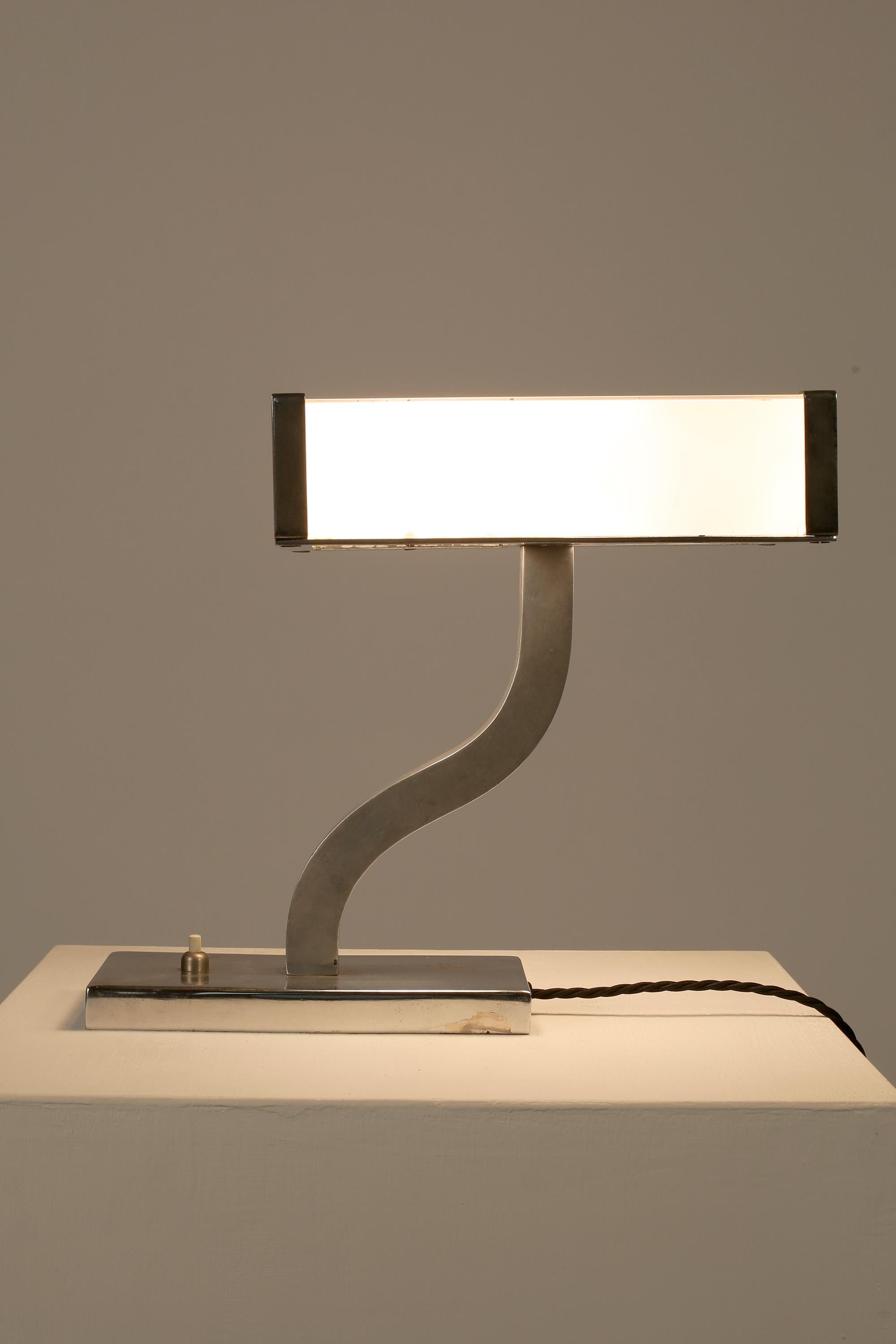 A rare modernist table lamp in chrome-plated metal with a diffusing shade in white glass panels, sitting atop a serpentine stem which extends from a simple rectangular base. Italian, c. 1930s.