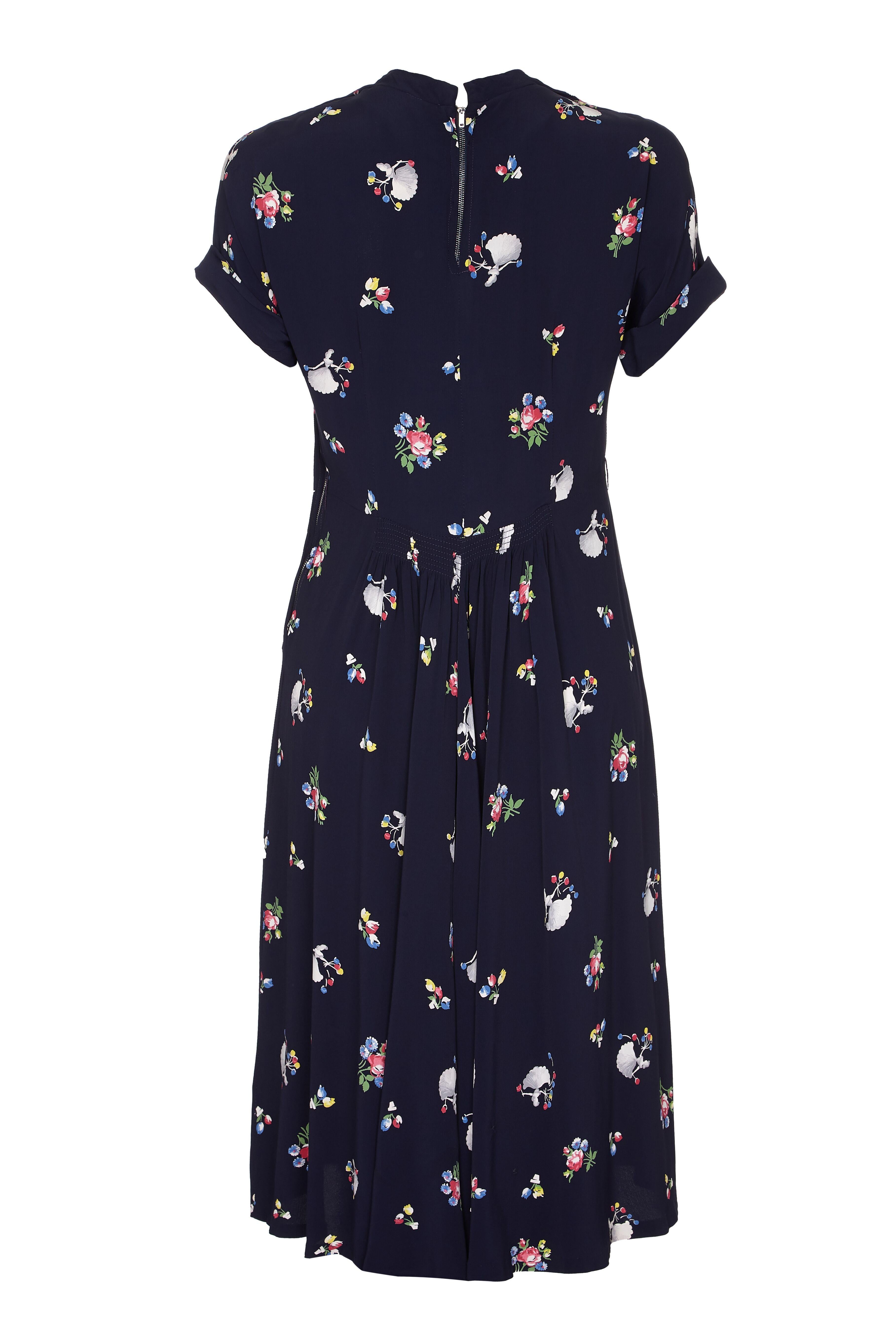 This beautiful vintage 1940s tea dress has a rare and unusual ballerina novelty print. The lightweight rayon fabric is predominantly navy, depicting bouquets of flowers in pink, blue yellow and green interspersed with tiny ballerina figures. The