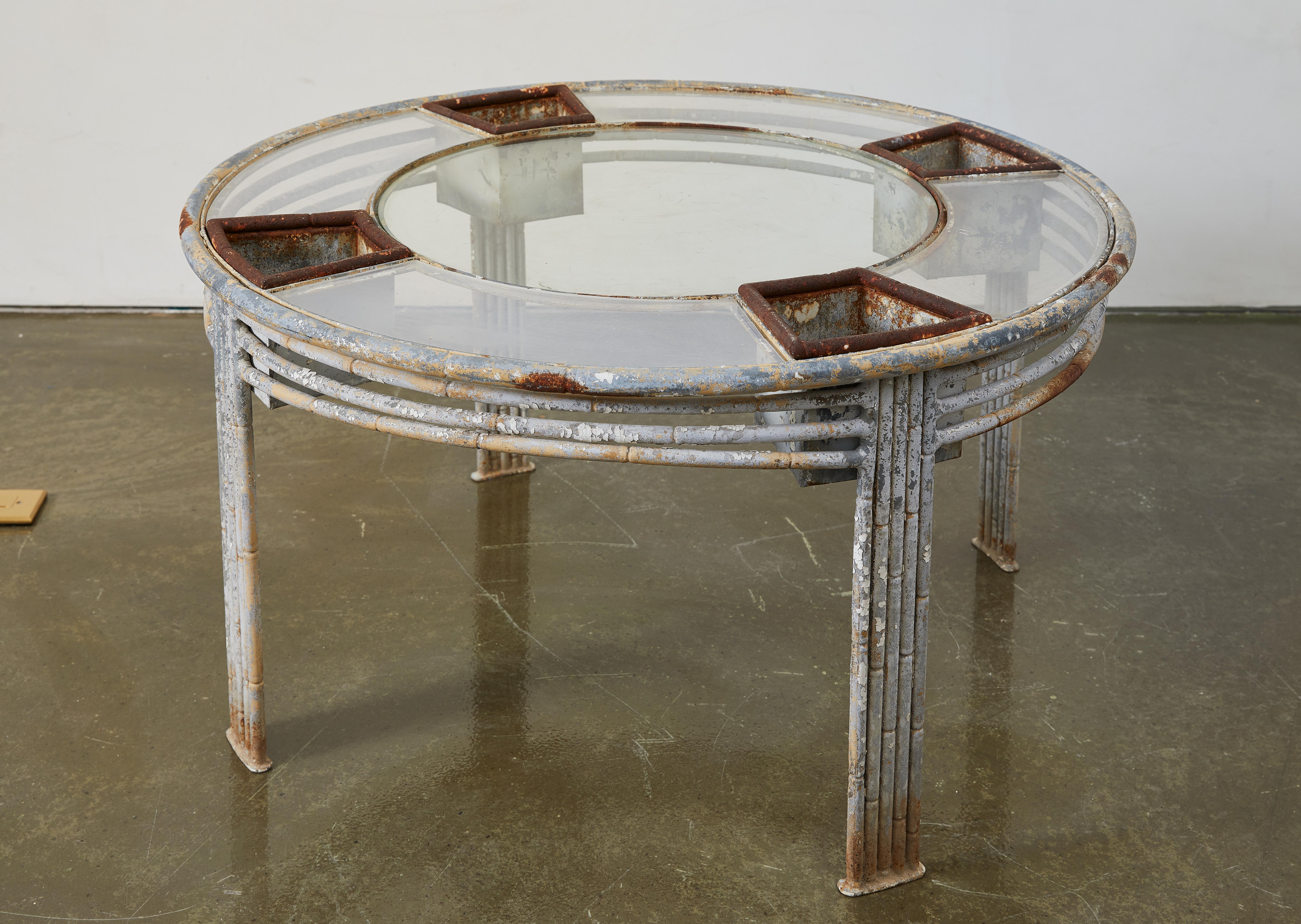 Dieser ungewöhnliche Tisch aus den 1940er Jahren aus Zink und Glas mit Acrylprofilen verbindet industrielles Design mit organischer Funktionalität. Die runde Tischplatte mit eingebauten Pflanzfächern bietet eine einzigartige Möglichkeit, Grün in