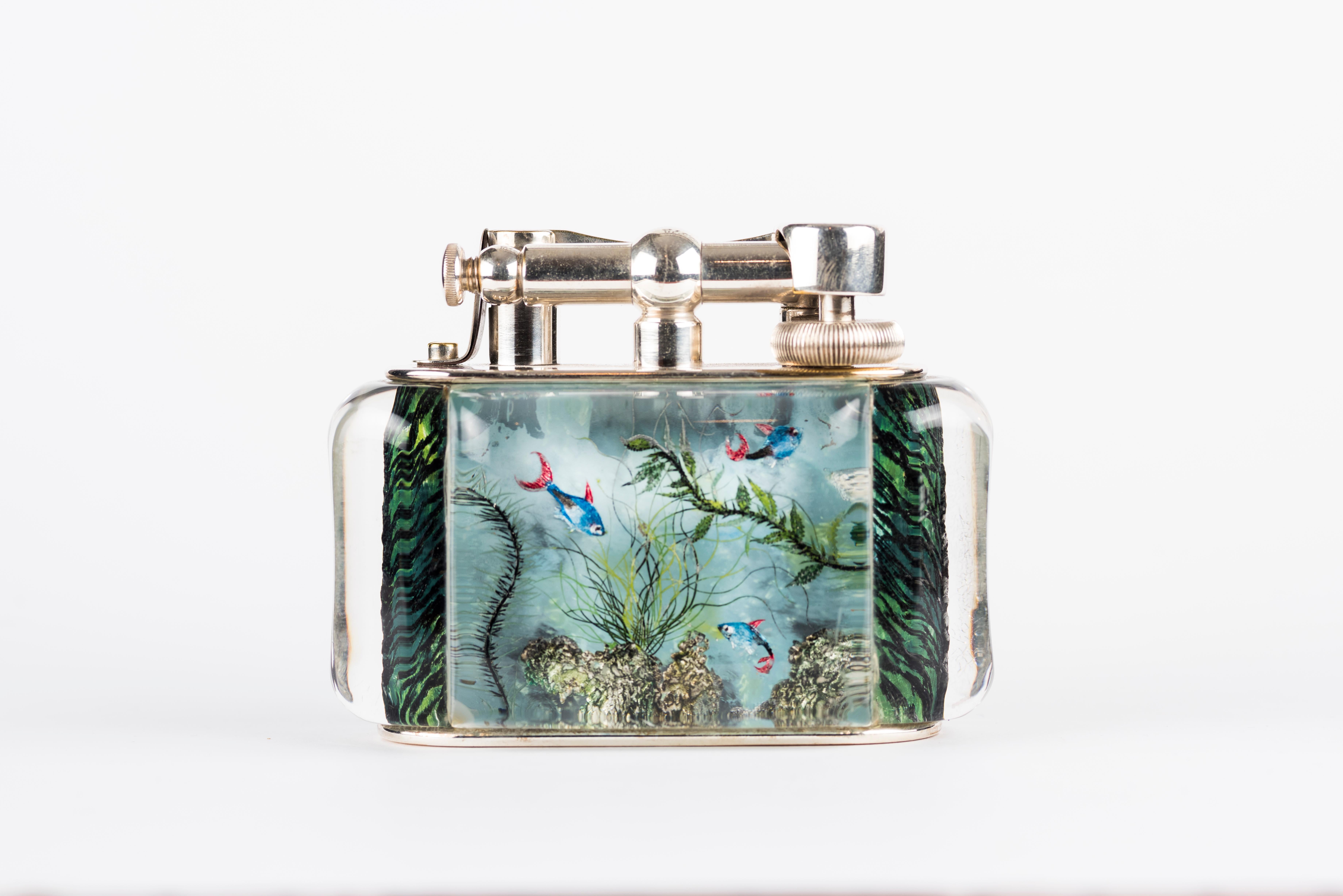 A rare 1950s Half-Giant Dunhill Aquarium table lighter (made in England) with silver-plated metal work 
Each of these lighters are very rare and unique as they were hand carved and painted and no one look exactly similar.

Ben Shillingford