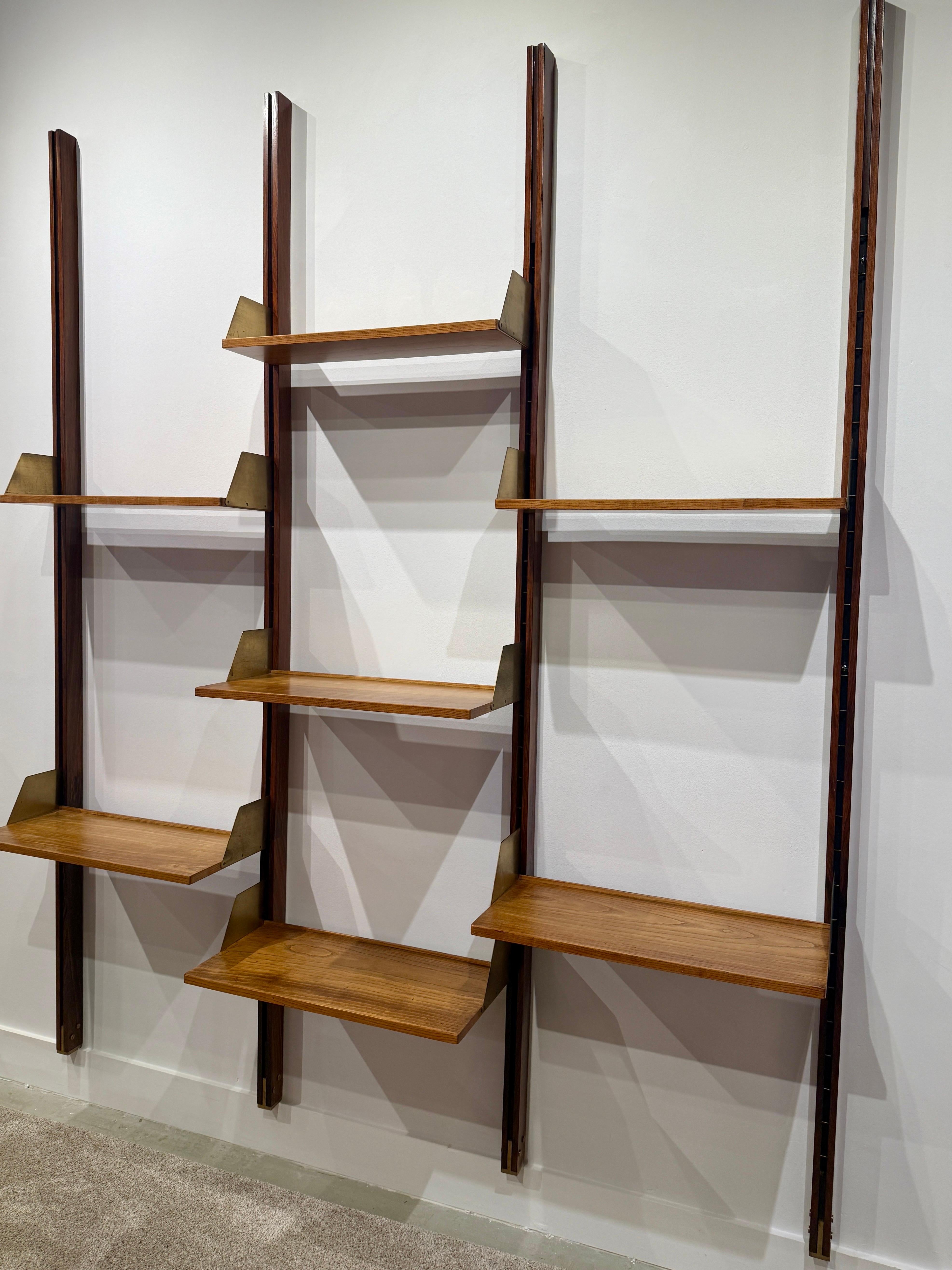 This fantastic 1950's Italian crafted mahogany wood slat and floating walnut shelf system features 7 wood and brass shelves of differing depths for books, art, sculpture, etc.  Comprised of three (4) wall mounted wood slats the shelves can be
