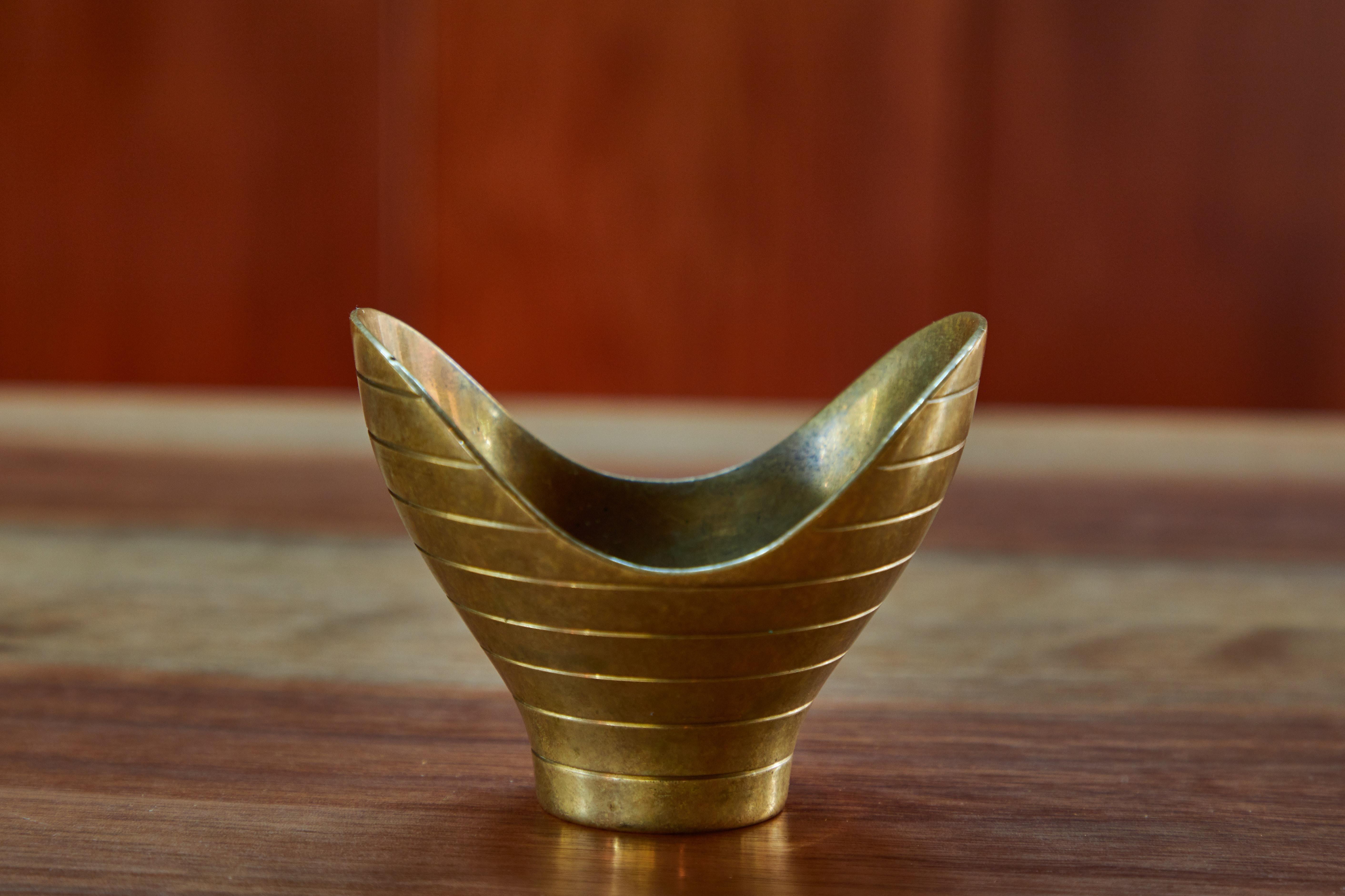 Rare 1950s Paavo Tynell Model AB-9Anamorphic brass bowl for Taito Oy. Executed in solid and lovely patinated brass. Manufactured by Taito Oy in the late 1940s or early 1950s, this is a fine example of a Tynell's iconic design. 

The undisputed