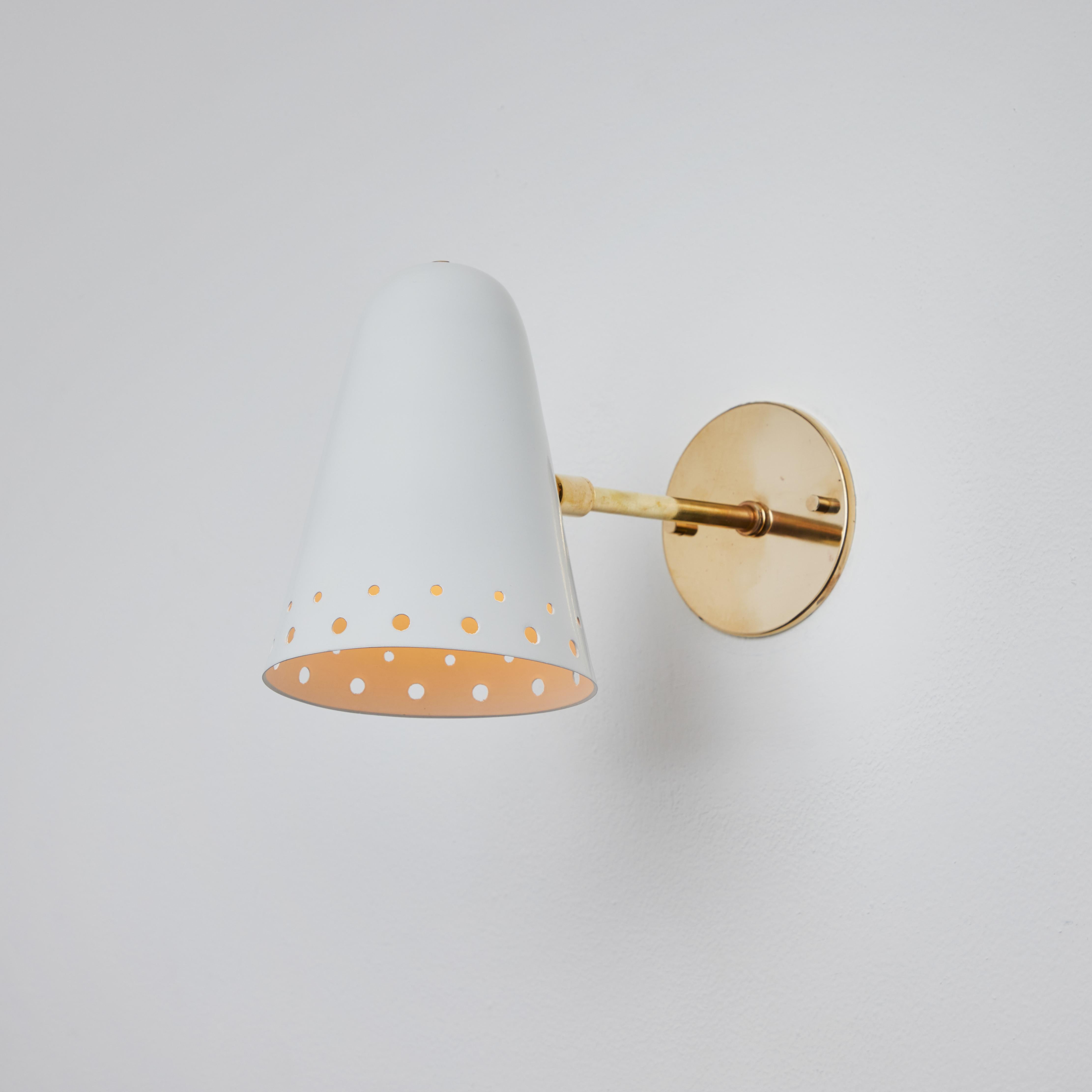 Rare 1950s Robert Mathieu perforated white metal and brass wall sconce. Executed in perforated white painted metal with custom period-style polished brass hardware and backplate. A clean yet functional wall lamp highly indicative of the iconic