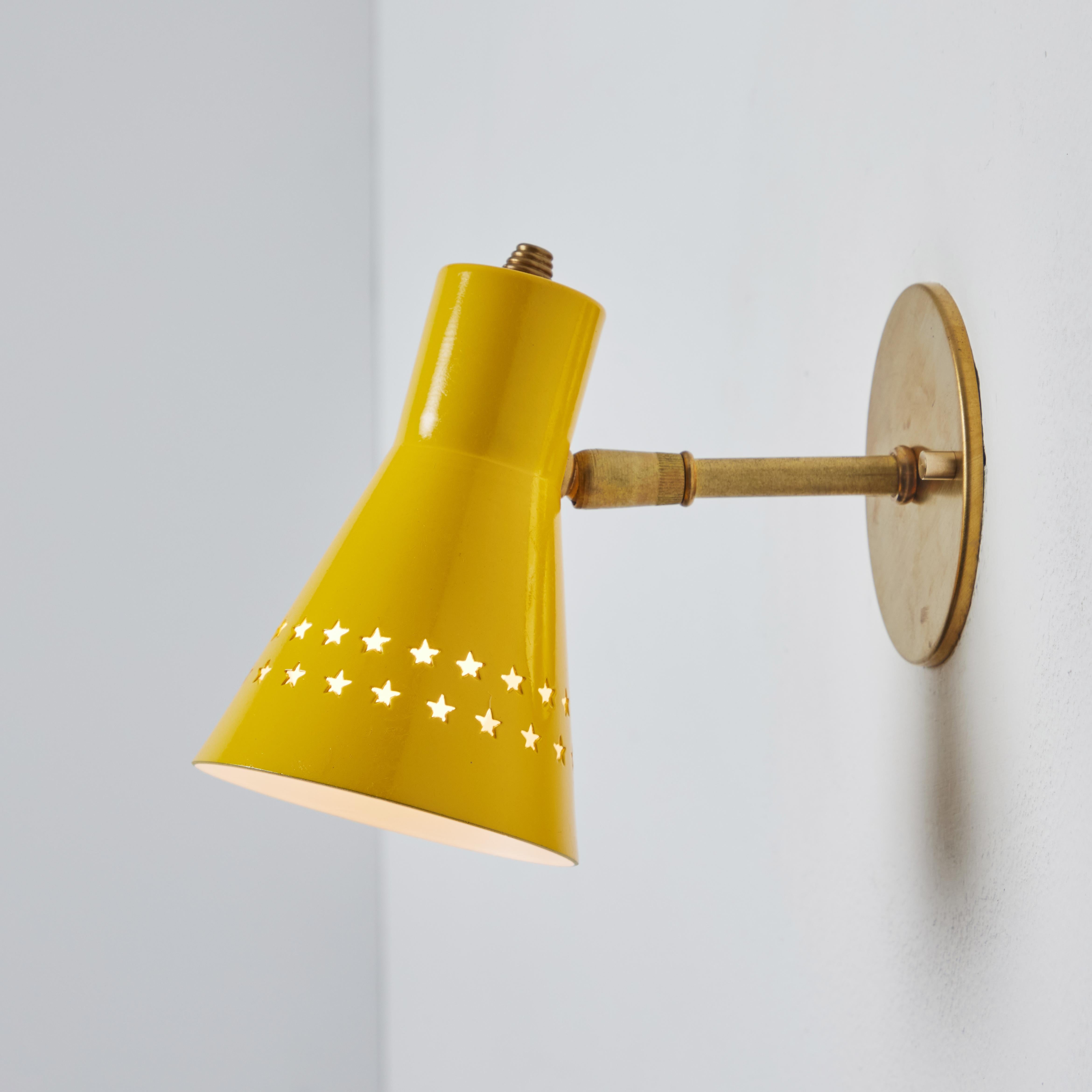 Rare 1950s Robert Mathieu perforated yellow metal and brass wall sconce. Executed in yellow painted metal shade with star perforations and polished brass hardware.  A bright and sculptural wall sconce highly indicative of the iconic mid-century
