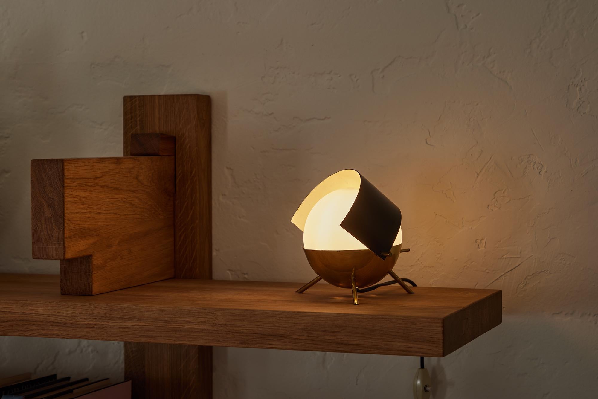Rare 1950s Stilux Milano Tripod 'Visor' Table Lamp. This whimsical and sculptural lamp is executed in opaline glass, attractively patinated brass and black painted metal adjustable visor in very good vintage condition. Characteristic of the highly