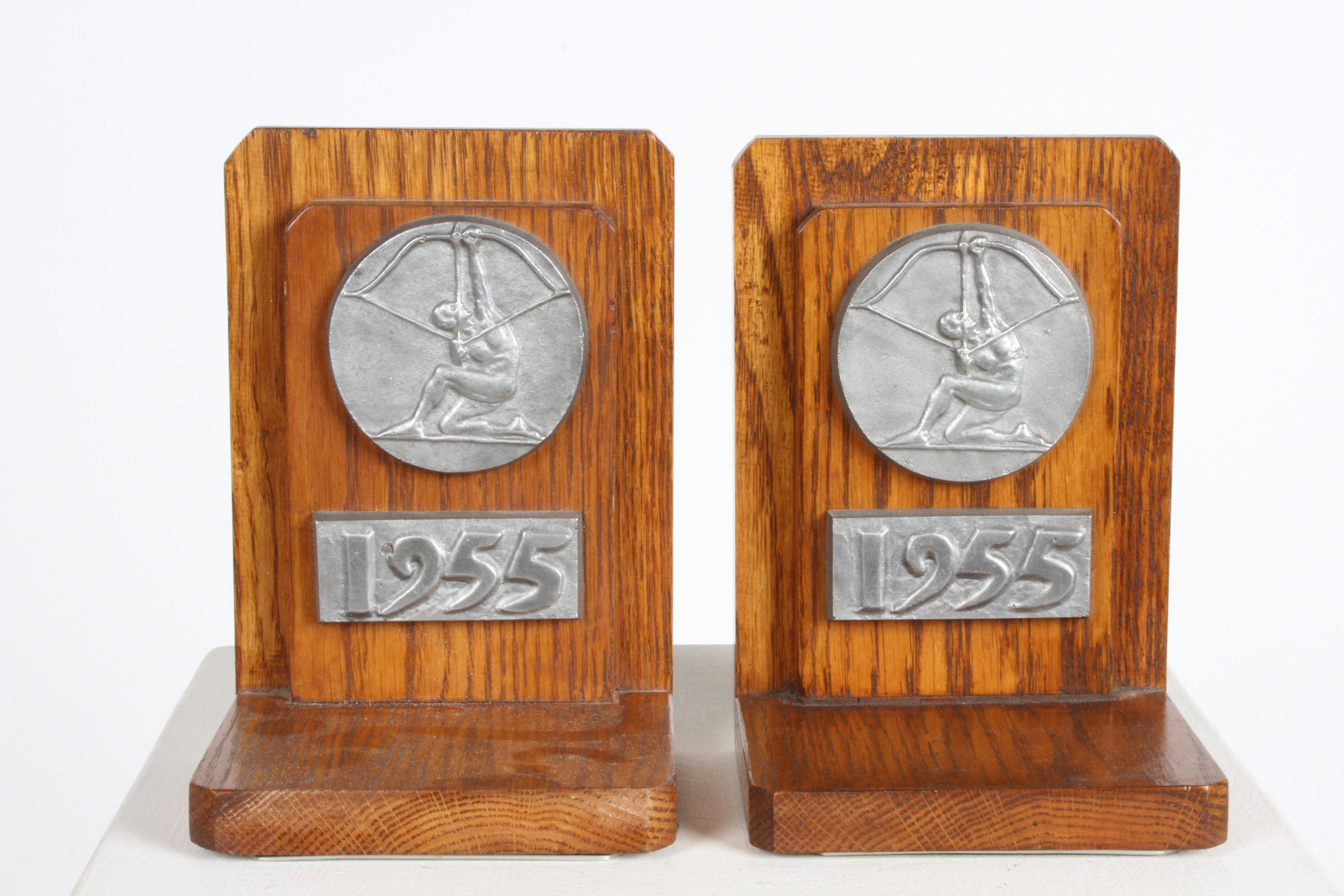 Rare pair of bookends with cast aluminum seal of Cranbrook School - Aim High logo and the year 1955 mounted to the oak boards. The Aim High logo was designed by Eero Saarinen, son of Eliel Saarinen who designed the schools campus and was president