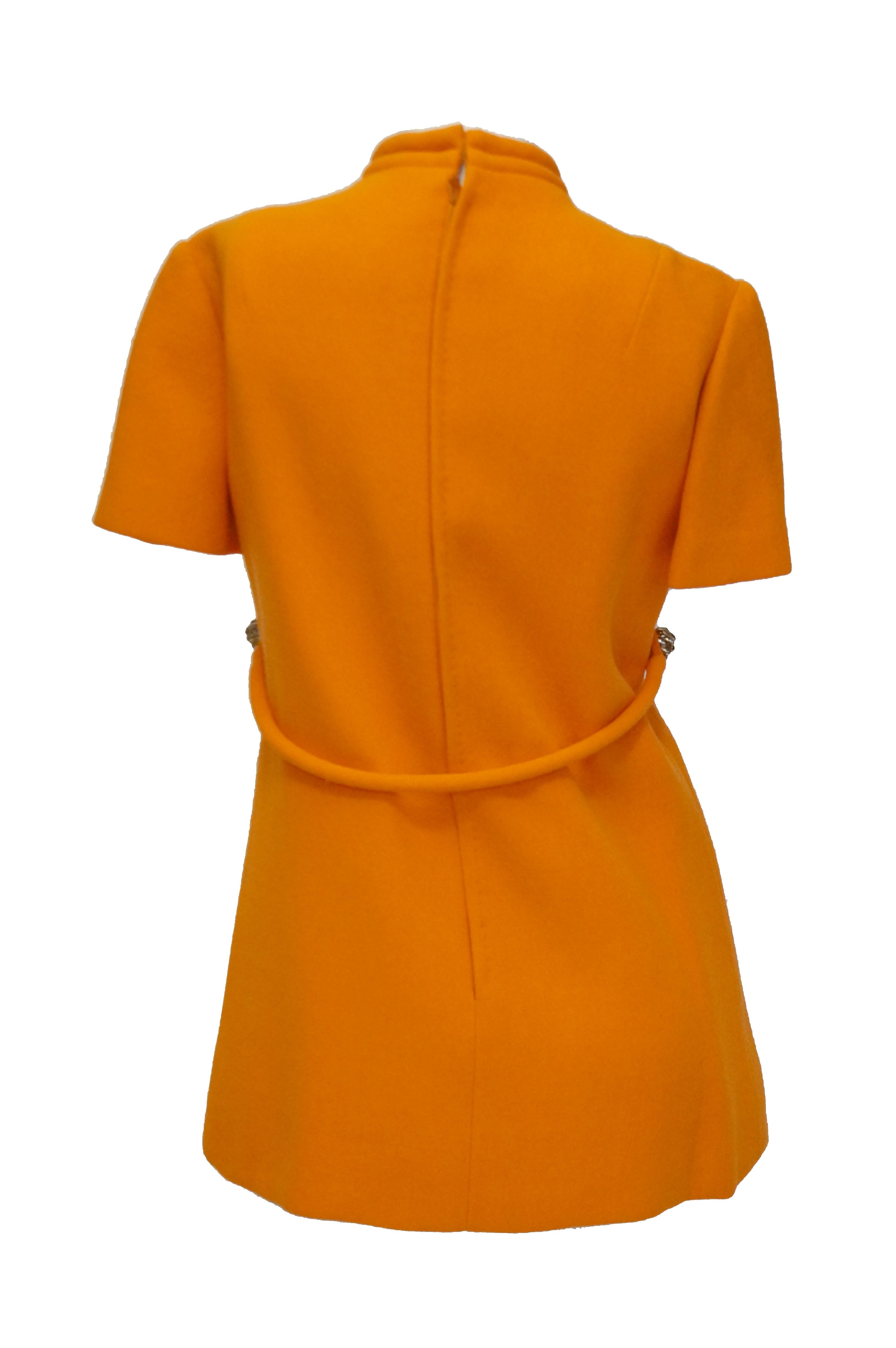 1960s Bill Blass Orange Mod Mini Dress with Nugget Belt Detail

Fantastic futuristic bright orange dress by Bill Blass! The dress is mini length, with short sleeves, a high faux turtle neckline large box pleating on the front. The bodice has an