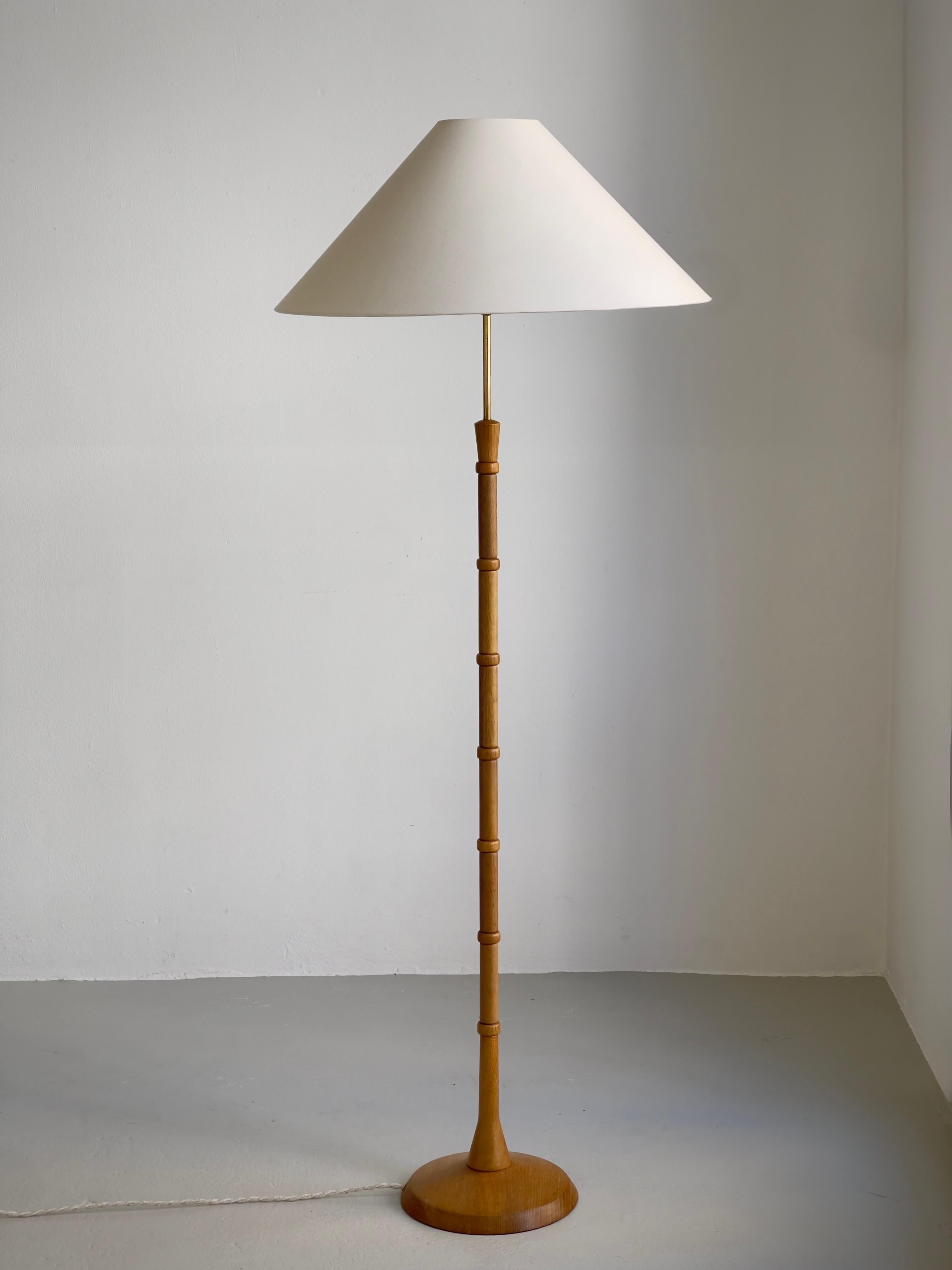 This striking Danish floor lamp from the 1960s embodies the refined craftsmanship and sculptural sensibility that define the midcentury modern movement in Scandinavia. The lamp’s shaft is composed of individually carved oak segments, rhythmically