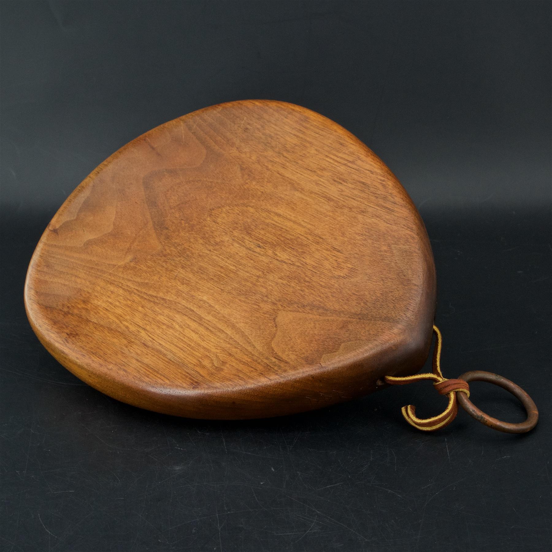 Modernist tear drop form. Dirk Rosse (1925-2014) was an exhibited studio furniture maker. Cutting board in walnut, signed with his DDR mark to edge. 13 inches in length total when hung on wall with brass ring.