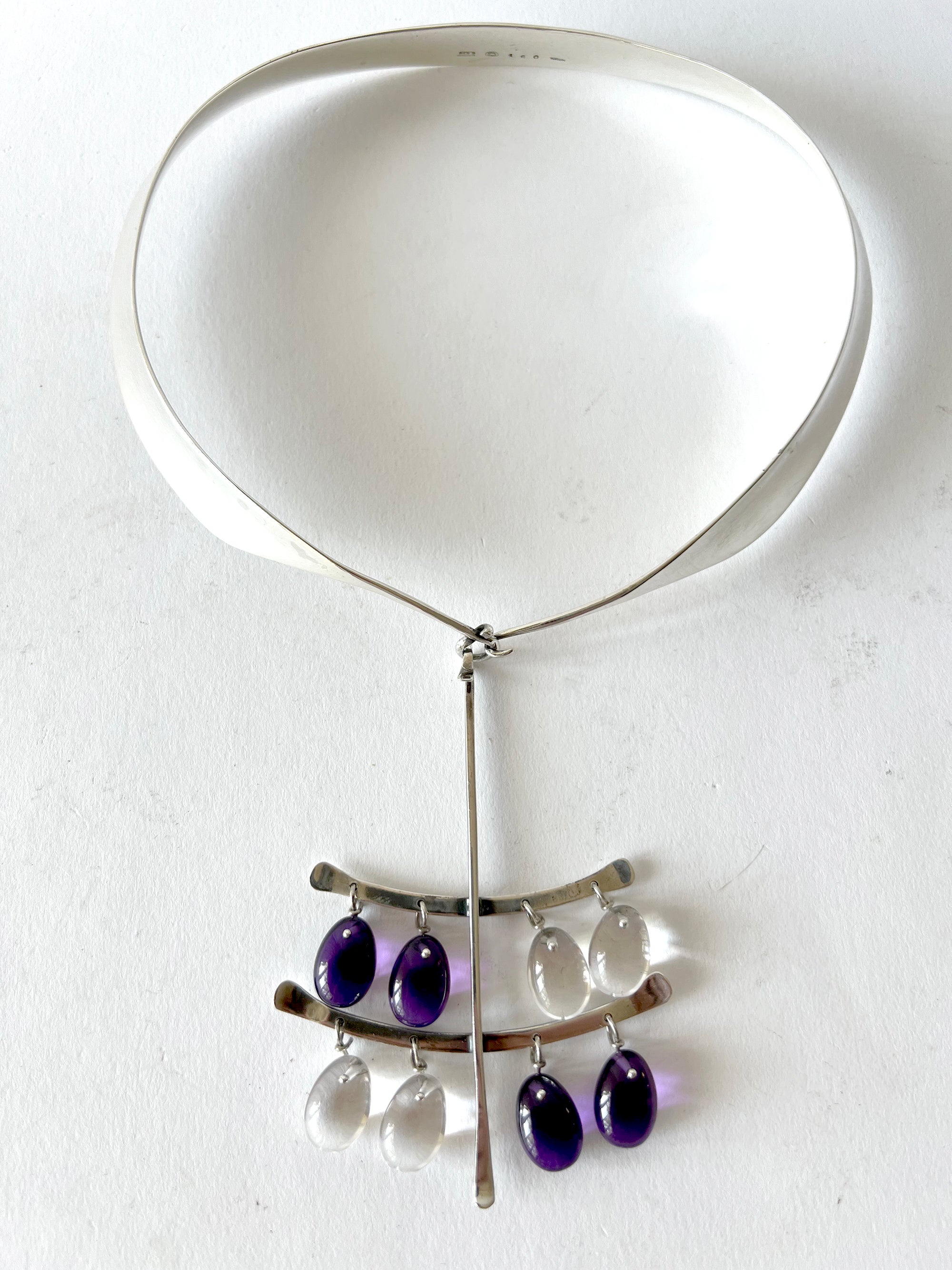 A rare, large pendant of teardrop shaped amethyst and rock quartz polished stones fastened by silver hooks. Pendant suspends from a sterling silver collar, all designed by Vivianna Torun Bulow-Hube, 1960s.  

Pendant measures 4