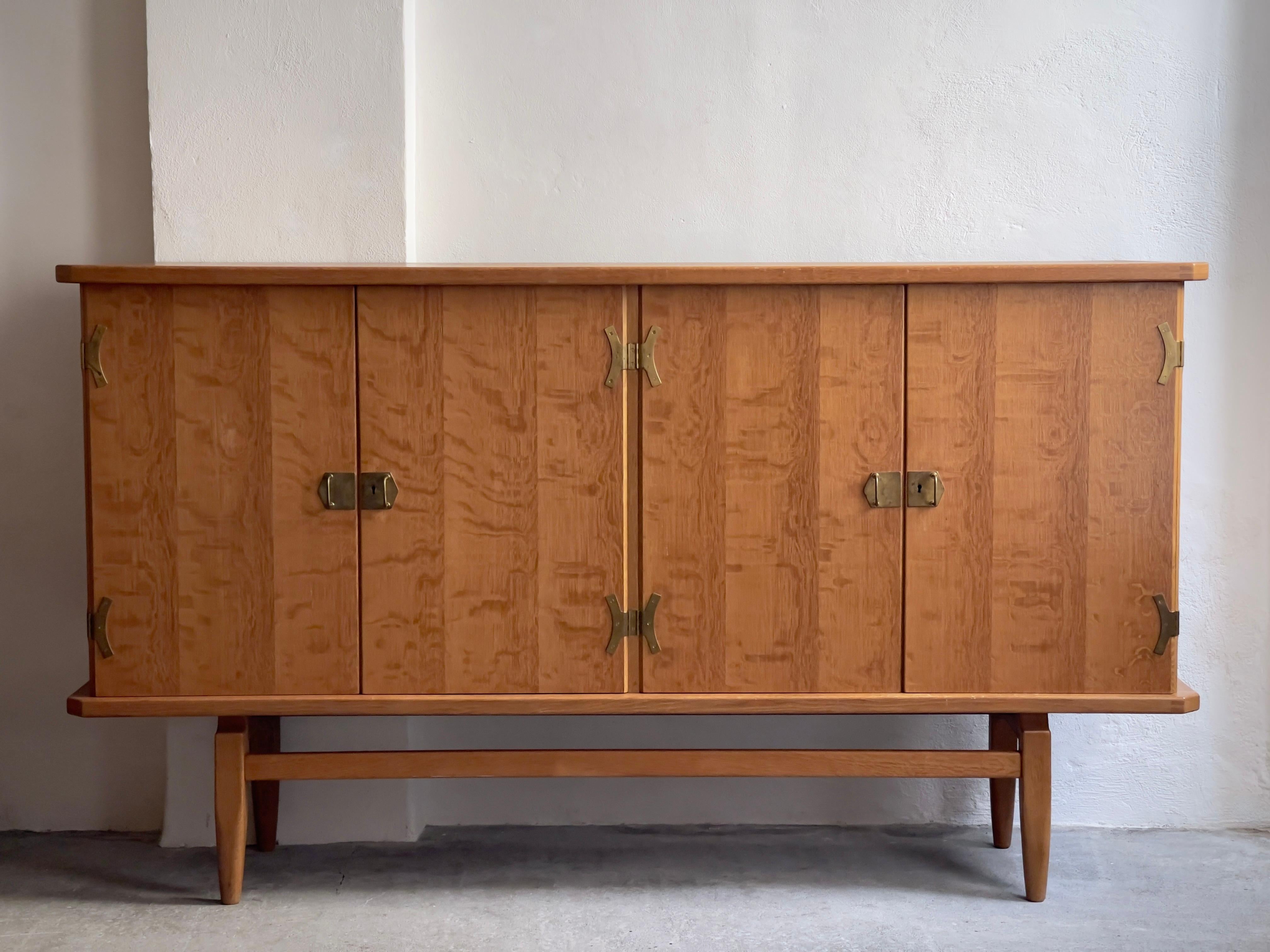 A rare 1970s Danish oak sideboard with brass brackets, masterfully created by the visionary Danish designer, Henning Kjærnulf. Also behind the iconic 