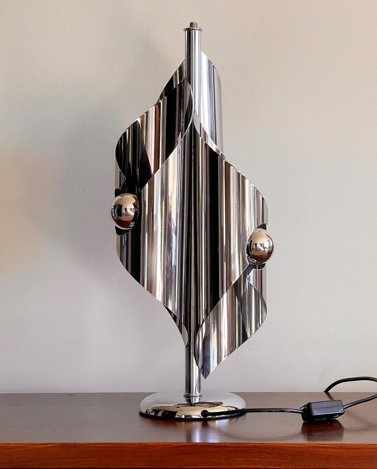 Rare 1970s Folded Chrome Lamp. Its origins can be traced back to both France and Italy. Crafted from polished stainless steel, the light reflects off the chrome surface and diffuses through three cylinders. A functional lamp at night and a