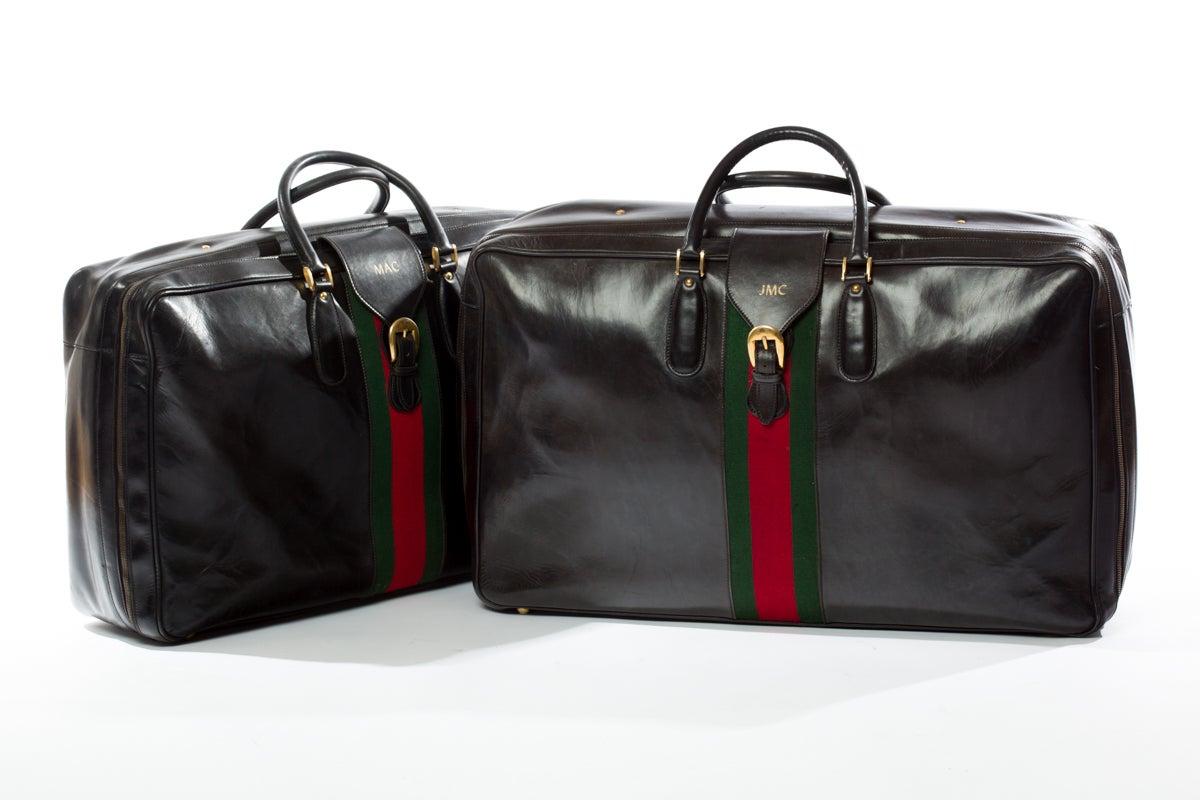 Pair of rare original Gucci black leather suitcases with Classic red and green Gucci stripe, leather handles and brass buckles and lock. Interior features black leather straps.
Gold stenciled label, Gucci, made in Italy.
Smaller bag measures 18
