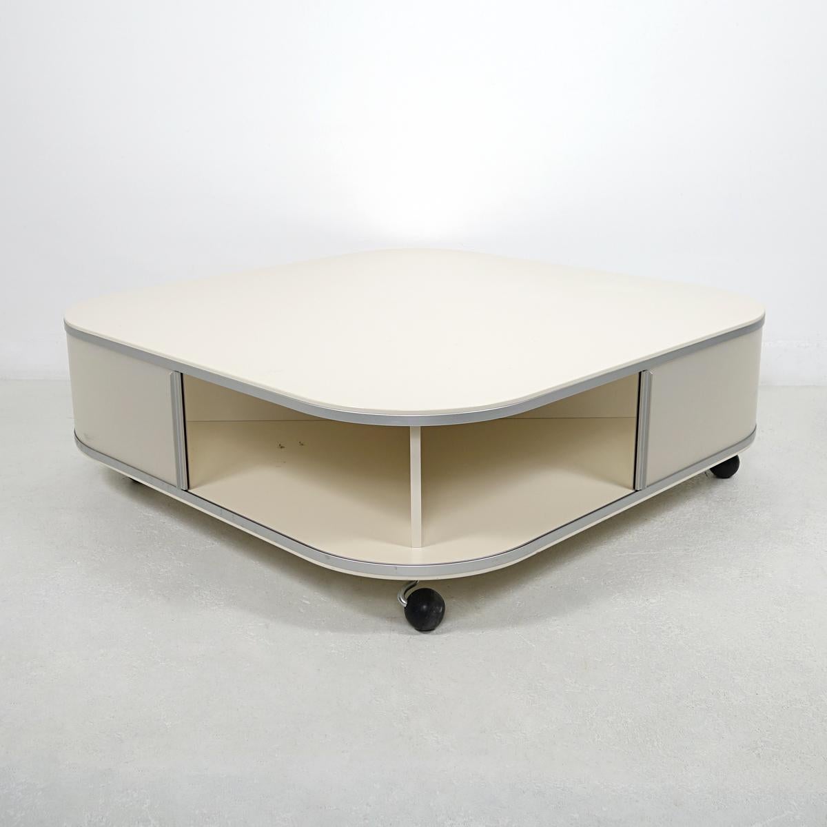 This coffee table manufactured by the famous Dutch label Pastoe probably dates back to the 1980s.
The table made of off-white laminated wood sits on four wheels, making it easy to move. Its square shaped is softened by its round corners. Subtle