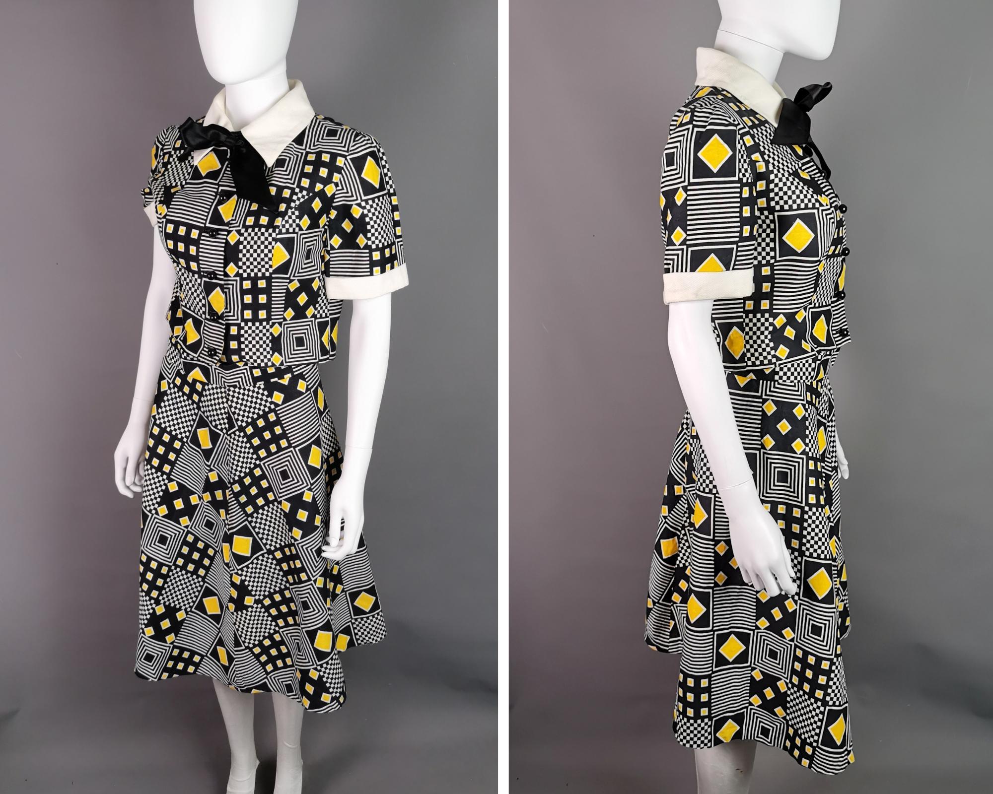 A fab vintage 1980s loud, Abstract print skirt suit / three piece skirt set.

Jazzy monochrome print with vibrant yellow accents.

The blouse has short boxy sleeves, black plastic buttons and is a short length with with a slinky black pussy bow tie