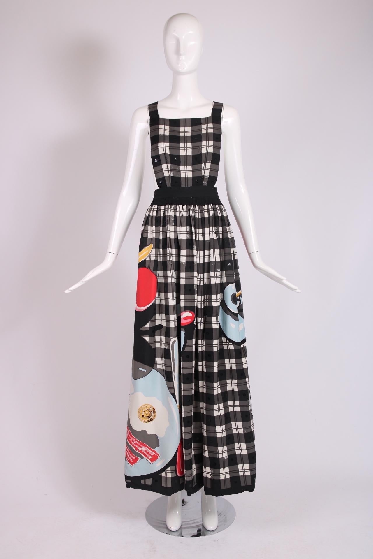 1982 S/S Michaele Vollbracht iconic black plaid on white pinafore dress featuring a breakfast scene replete with bacon and eggs w/yellow sequin yokes served on a plate, a steaming cup of coffee and silverware. Fabric tag 100% silk. Labeled size 10