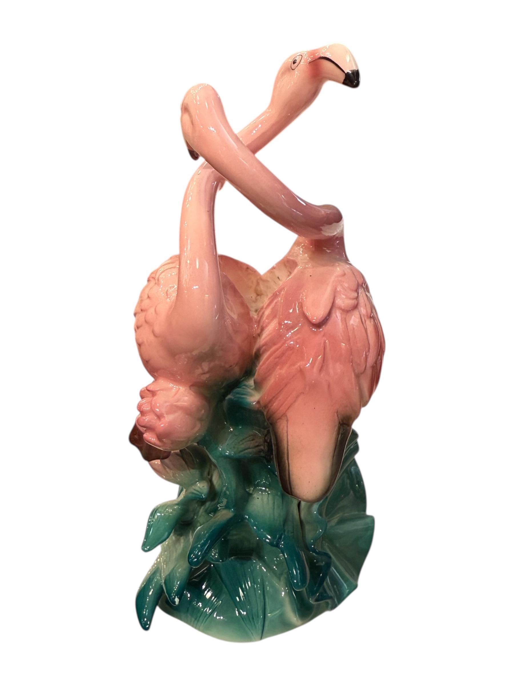 Add a splash of vintage tropical charm to your décor with this exquisite 1987 Fitz & Floyd Flamingo Candleholder. Crafted in stunning ceramic, this rare collectible features two elegant pink flamingos intertwined in a graceful pose, perched amidst