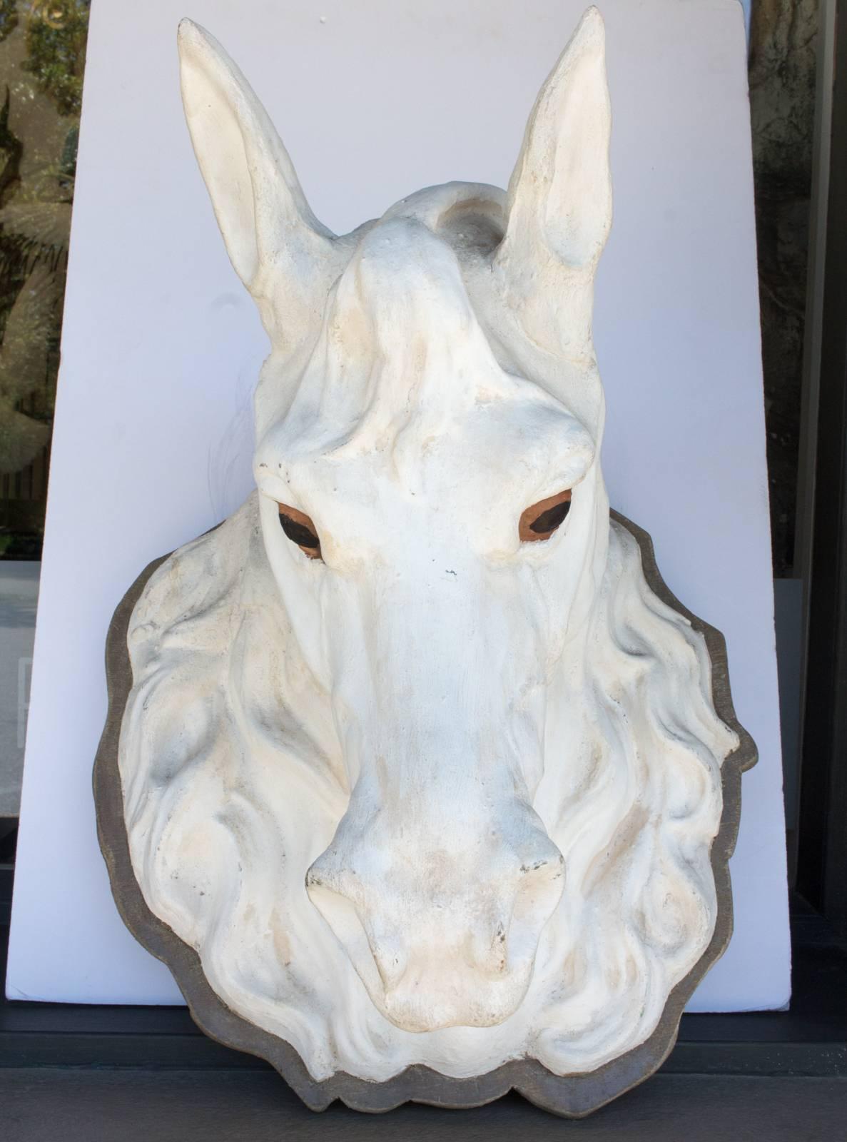 This 19th century trade sign in the shape of a horse head is handcrafted in zinc and painted white and once hung in a Parisian atelier. The eyes are a wonderful amber color and this piece is mounted onto a wood plaque. Uncovered in Paris, France,