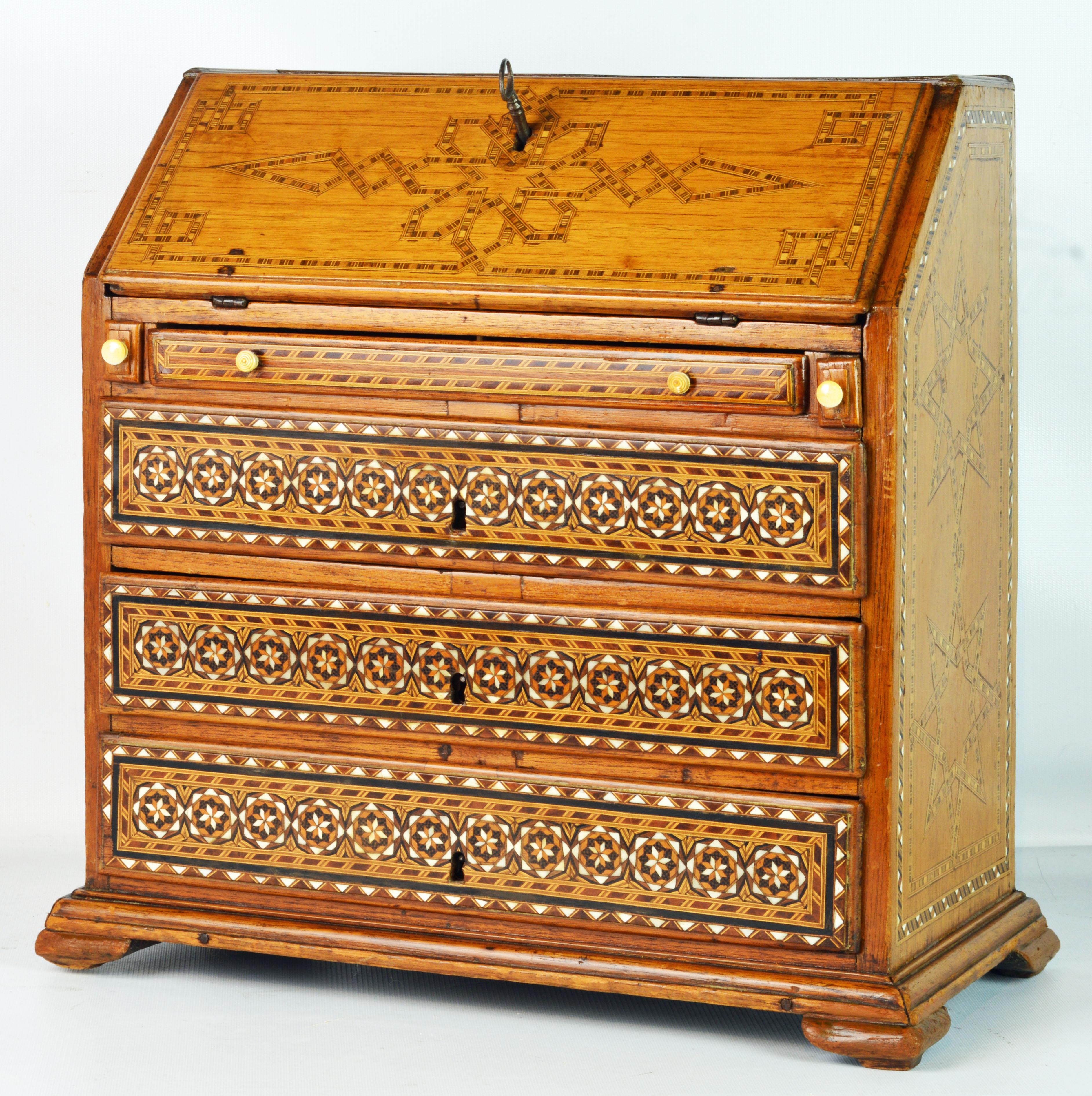 This rare and charming miniature slant front chest is created in the Georgian style with elaborate bone and veneer inlay as well as certain details in the oriental style. The chest features an inlaid slanted front opening up to an interior fitted
