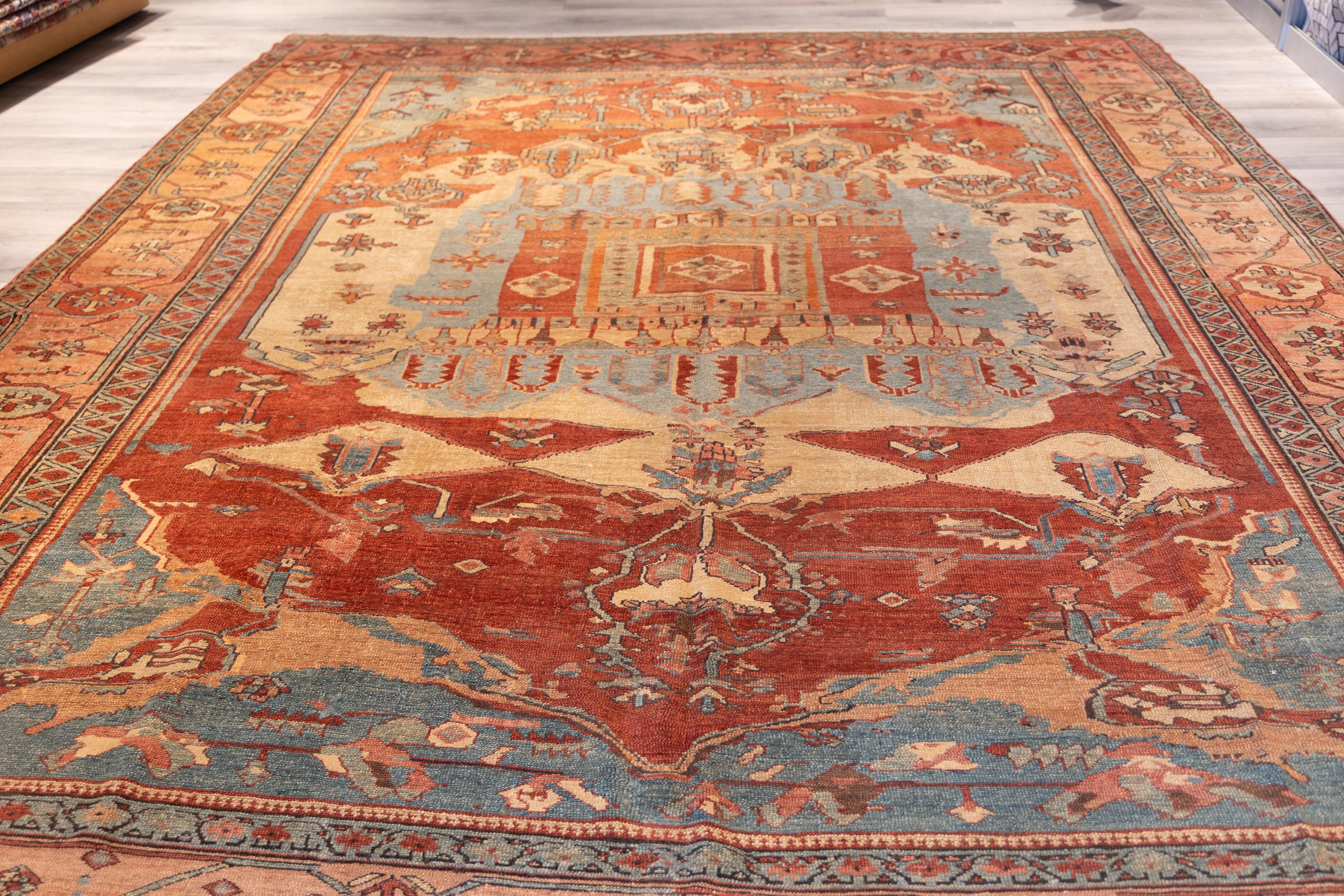 The design centers on a grand stepped medallion with a palmette and cruciform motif, framed by a balanced array of angular vines and stylized floral elements. The surrounding field, rendered in a harmonious blend of rust, pale blue, and soft ivory,