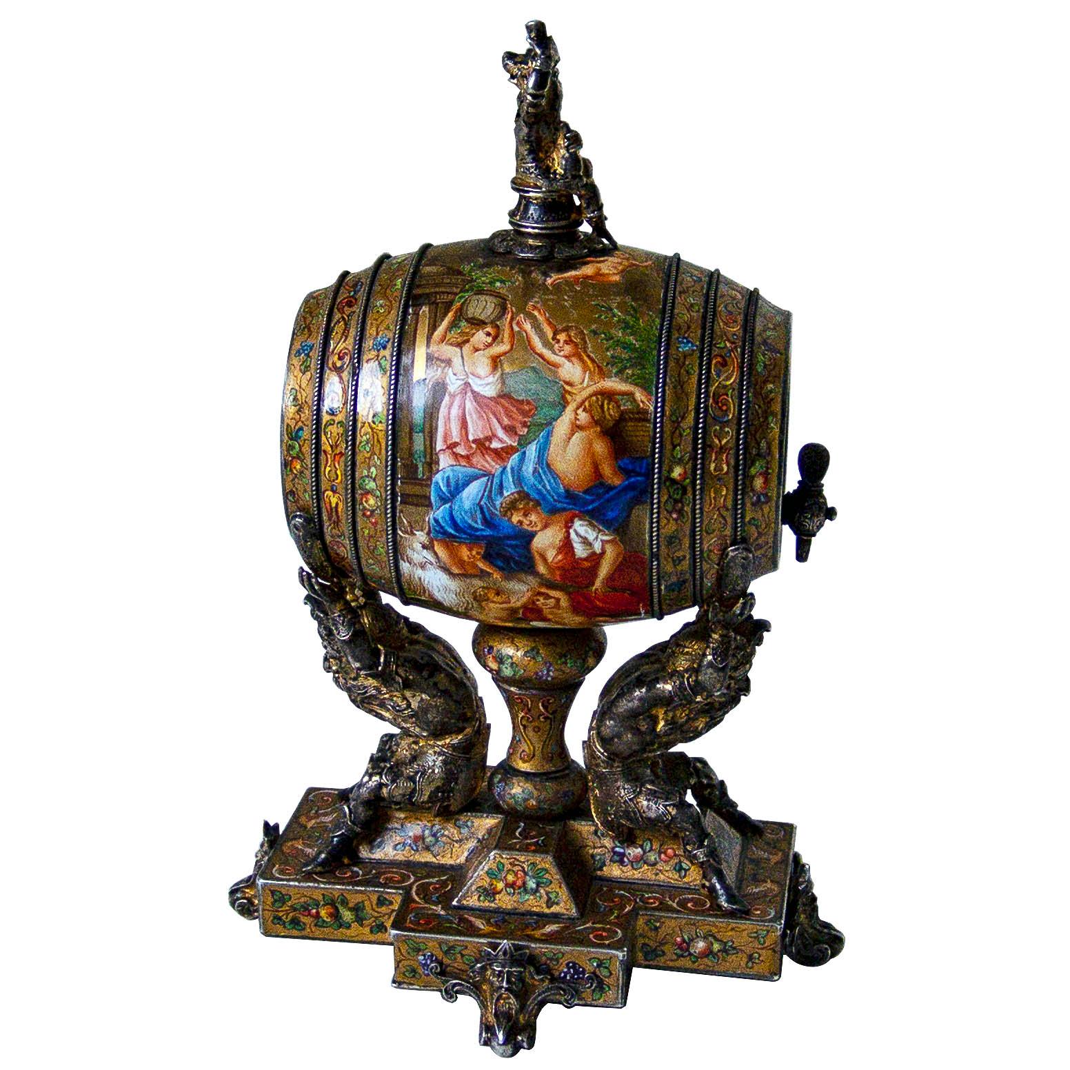 A beautifully enameled silver 'wine barrel' supported by the raised hands of two figures of Bacchus seated back to back either side of a central mount set on a stepped cruciform base which in turn is supported by four Bacchus mask feet. The barrel