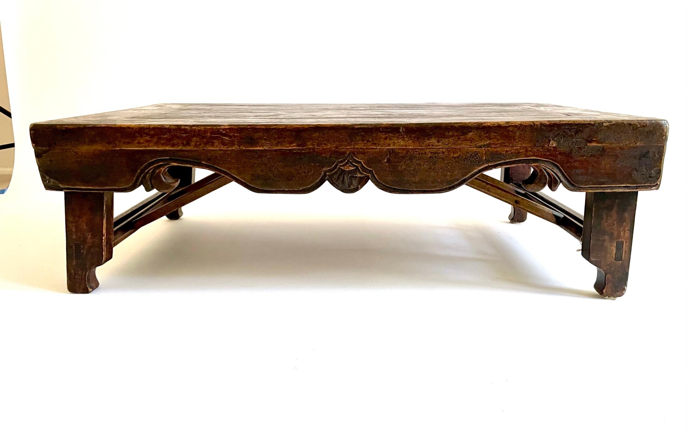 The unusual 19th century Kang Table (low table) is designed for the legs to fold into the table for storage when it’s not in use. It’s carved from Northern Elmwood (Yumu) and lacquered in a dark brown color and crafted with traditional Chinese