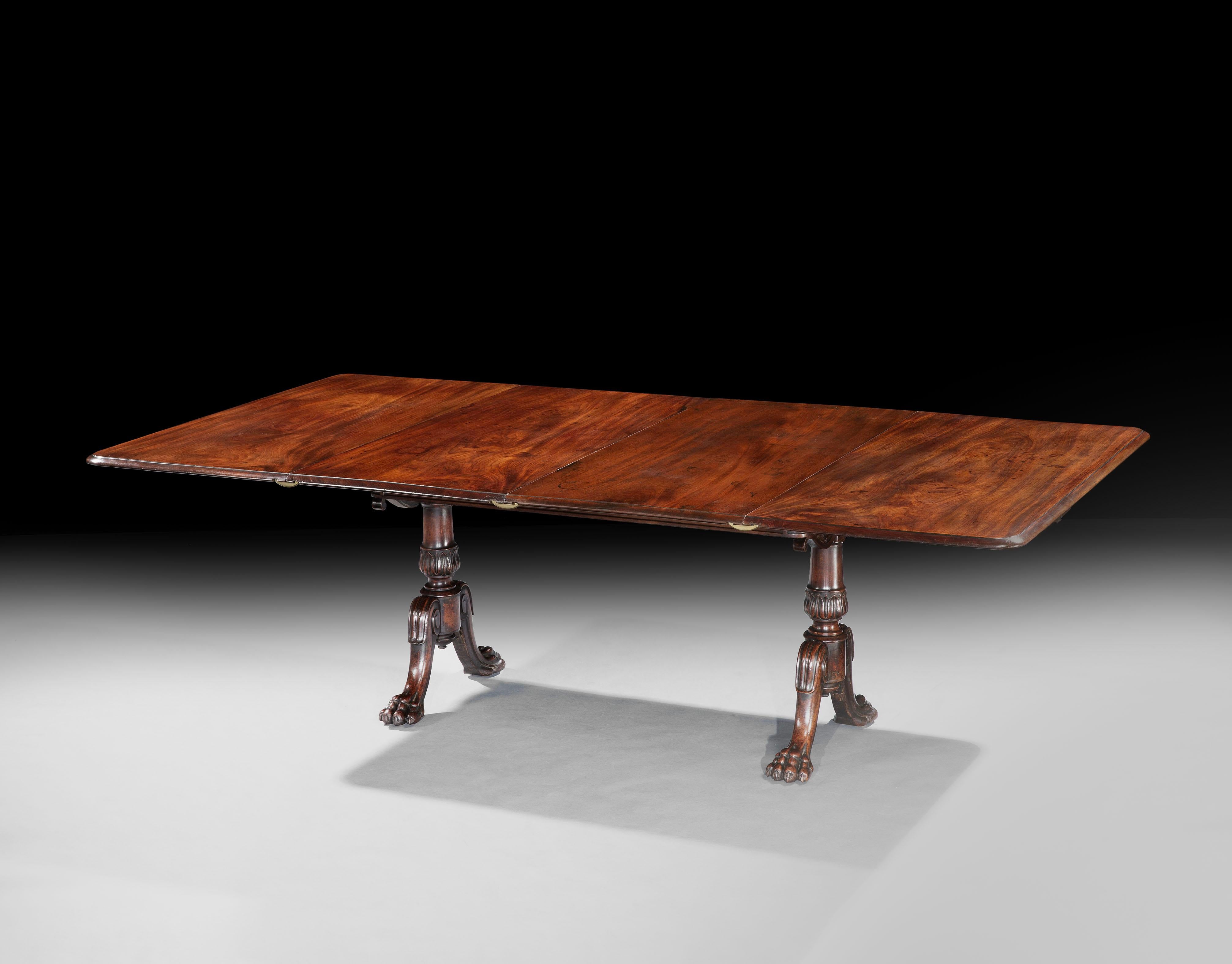 A rare patent extending dining table constructed from fine Cuban mahogany, when closed the table serves as an end-support table showcasing the handsome lotus-leaf carved and tapering legs terminating in pairs of lion paw feet; an ingenious