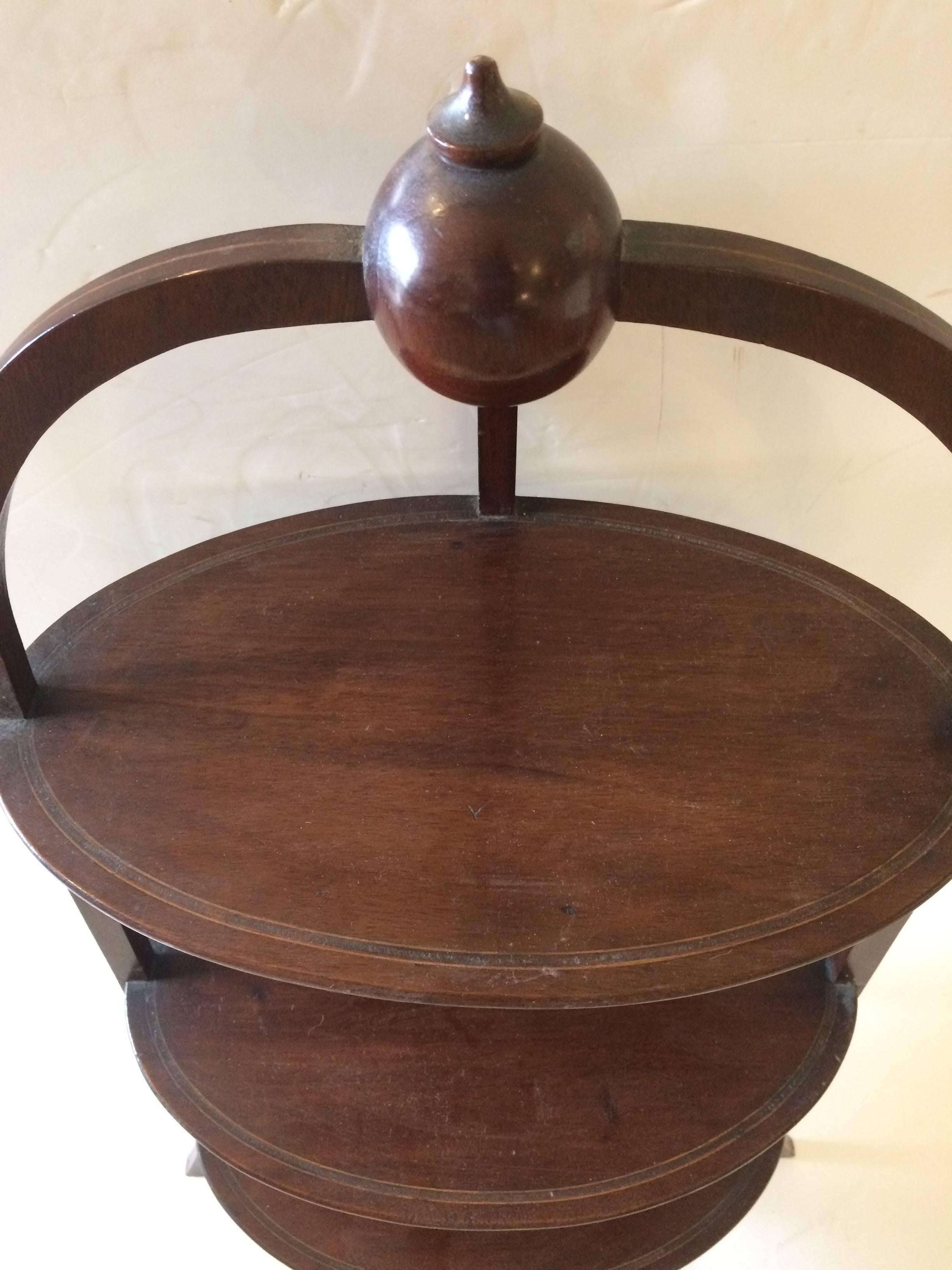 Gorgeous rare form muffin Stand or three-tier side table having three oval levels in mahogany with satinwood inlay and lovely curved legs, also with inlay on them vertically. Topped with a handsome ball. Distance between shelves is 10