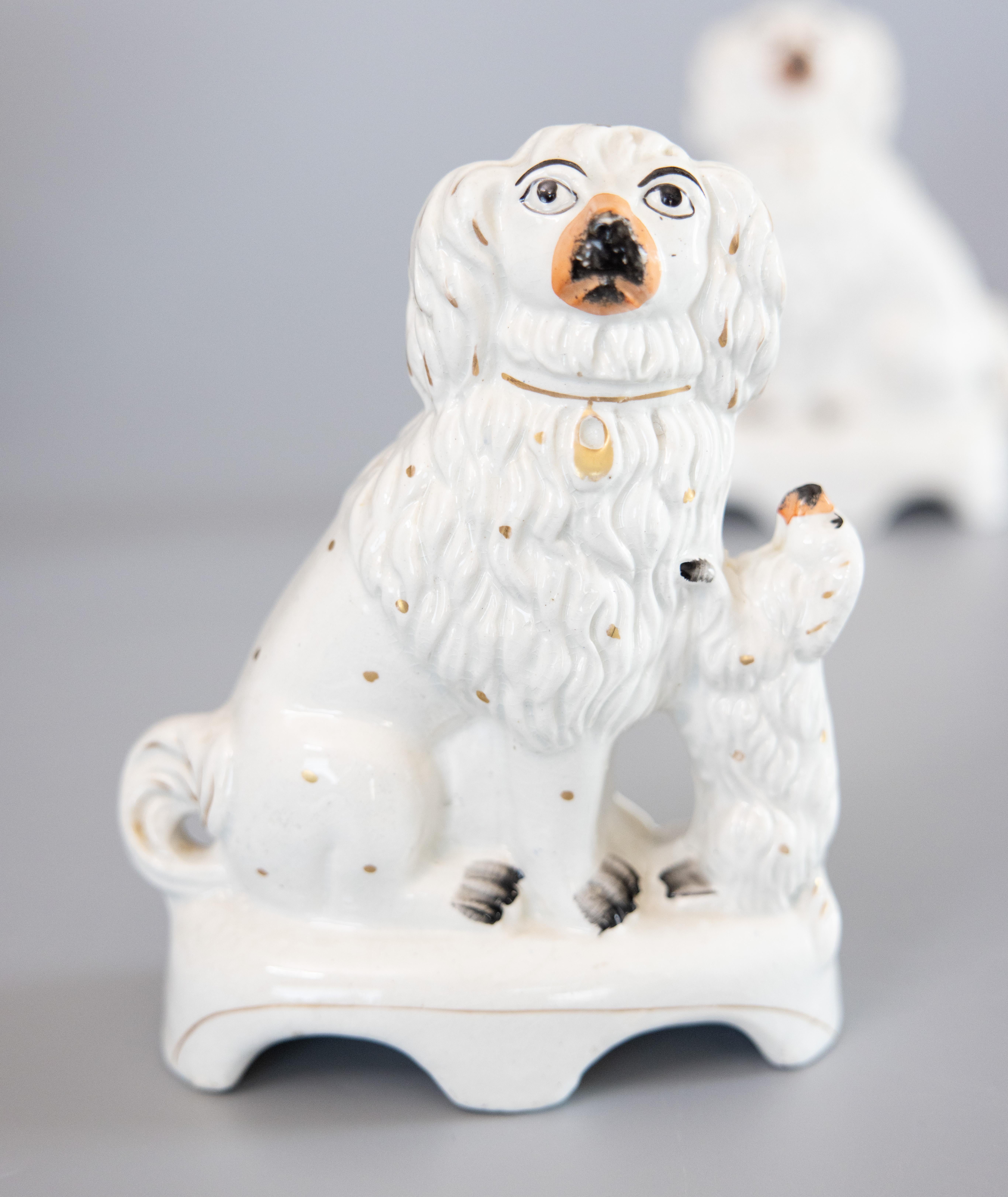A superb rare pair of antique 19th-Century English Staffordshire Spaniel dogs with pups. These charming dogs have fine hand painted details, gilt accents, and the sweetest expressions. It's hard not to be smitten! These figurines are in lovely