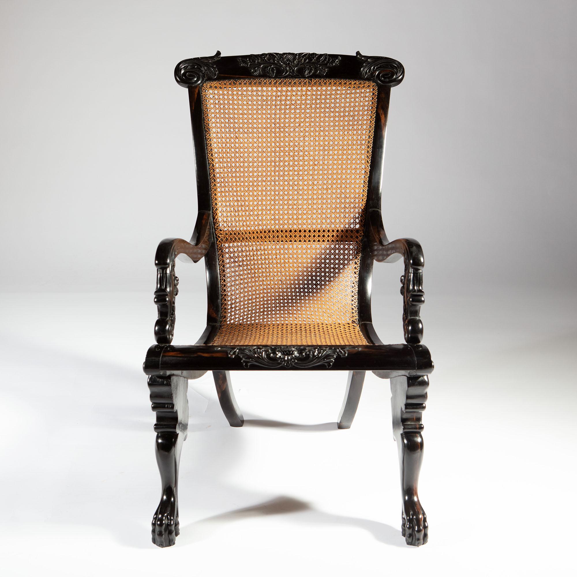 A very fine richly figured solid ebony Anglo-Indian armchair. The curved caned seat with an intricately carved floral top rail, sweeping highly sculptural arms and supported on boldly carved zoomorphic legs.
India, Ceylon, circa 1850

Measures: