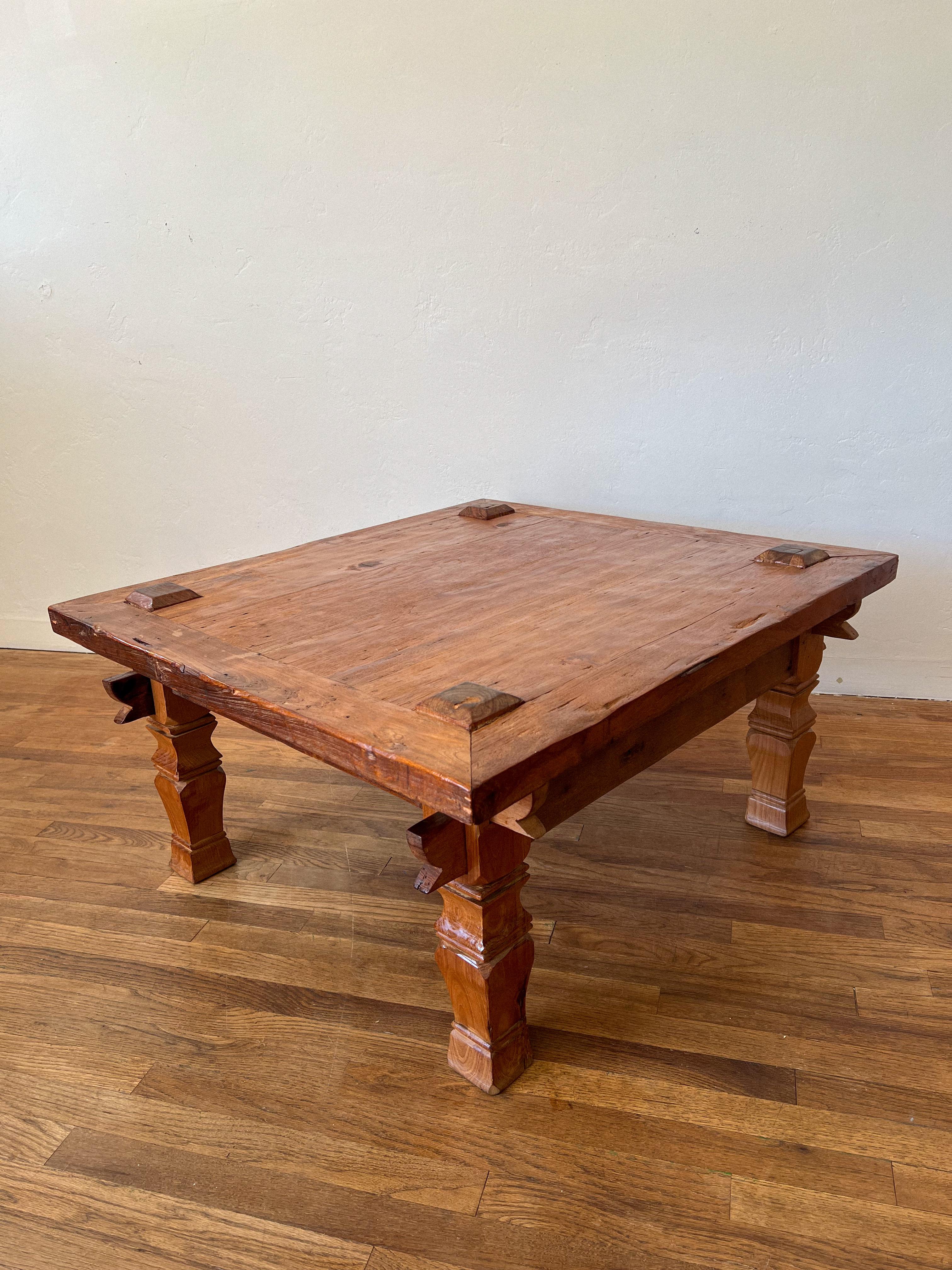Une table basse indonésienne de l'époque coloniale, fabriquée à la main en teck massif ancien, réputé pour sa densité, sa durabilité et sa patine chaleureuse. La pièce présente des assemblages d'angle à tenons et mortaises apparents, signe de