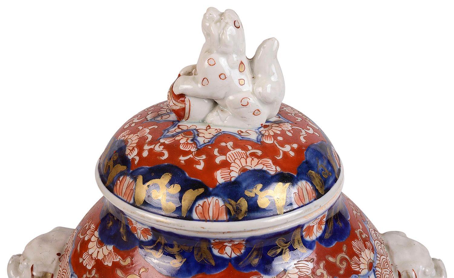 A rare and unusual 19th century Japanese Imari lidded vase having a `foo dogs to the lid and handles, classical bold blue and red `Imari colours with oriental motif designs, inset painted panels depicting exotic trees and flowers, raised on an
