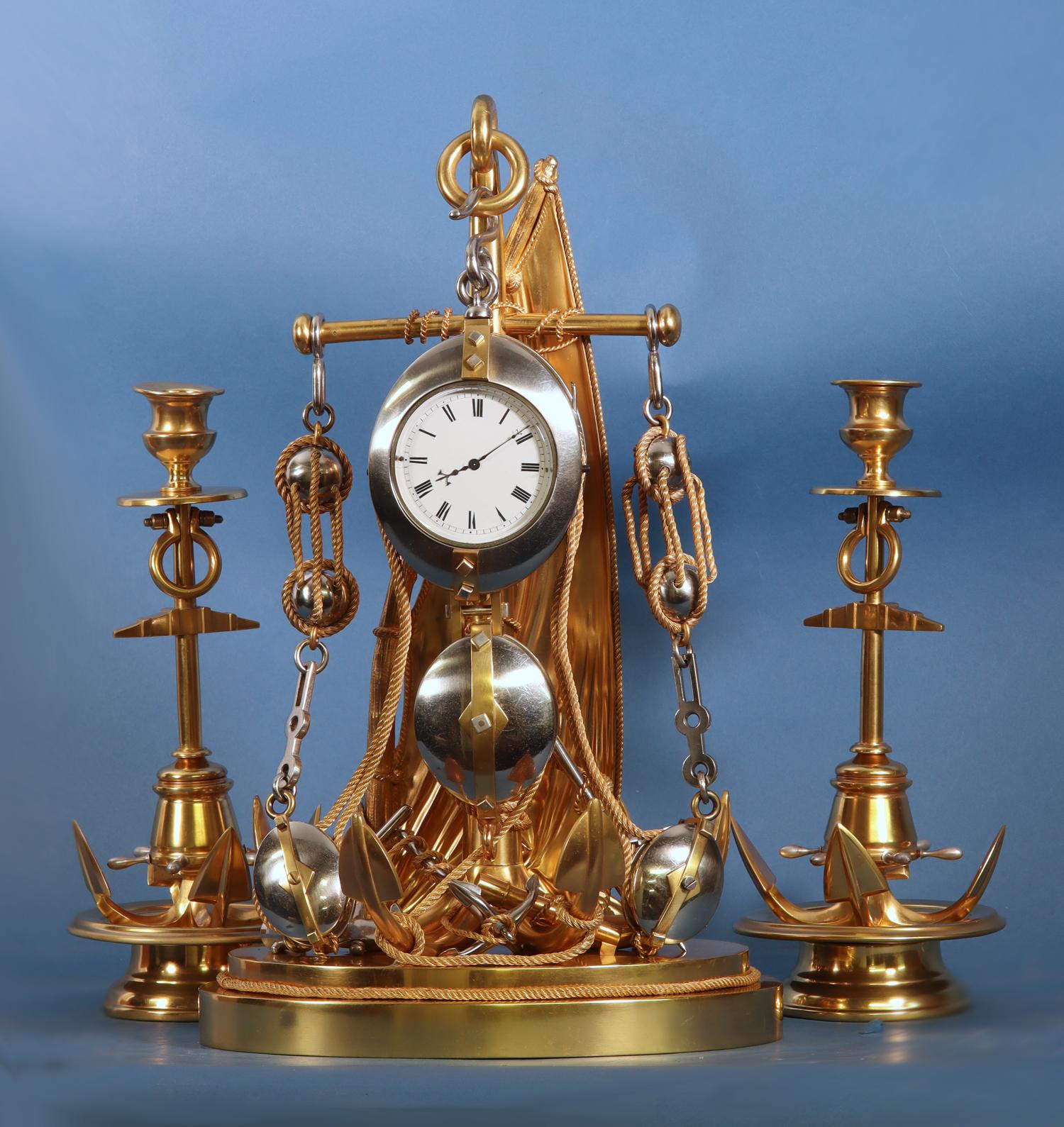 Rare gilt and silvered-bronze nautically themed mantle clock with the original side-pieces. It is composed of various ship inspired components that include a sail, anchors, block and tackles and twisting ropes. Both the clock and sidepieces are also