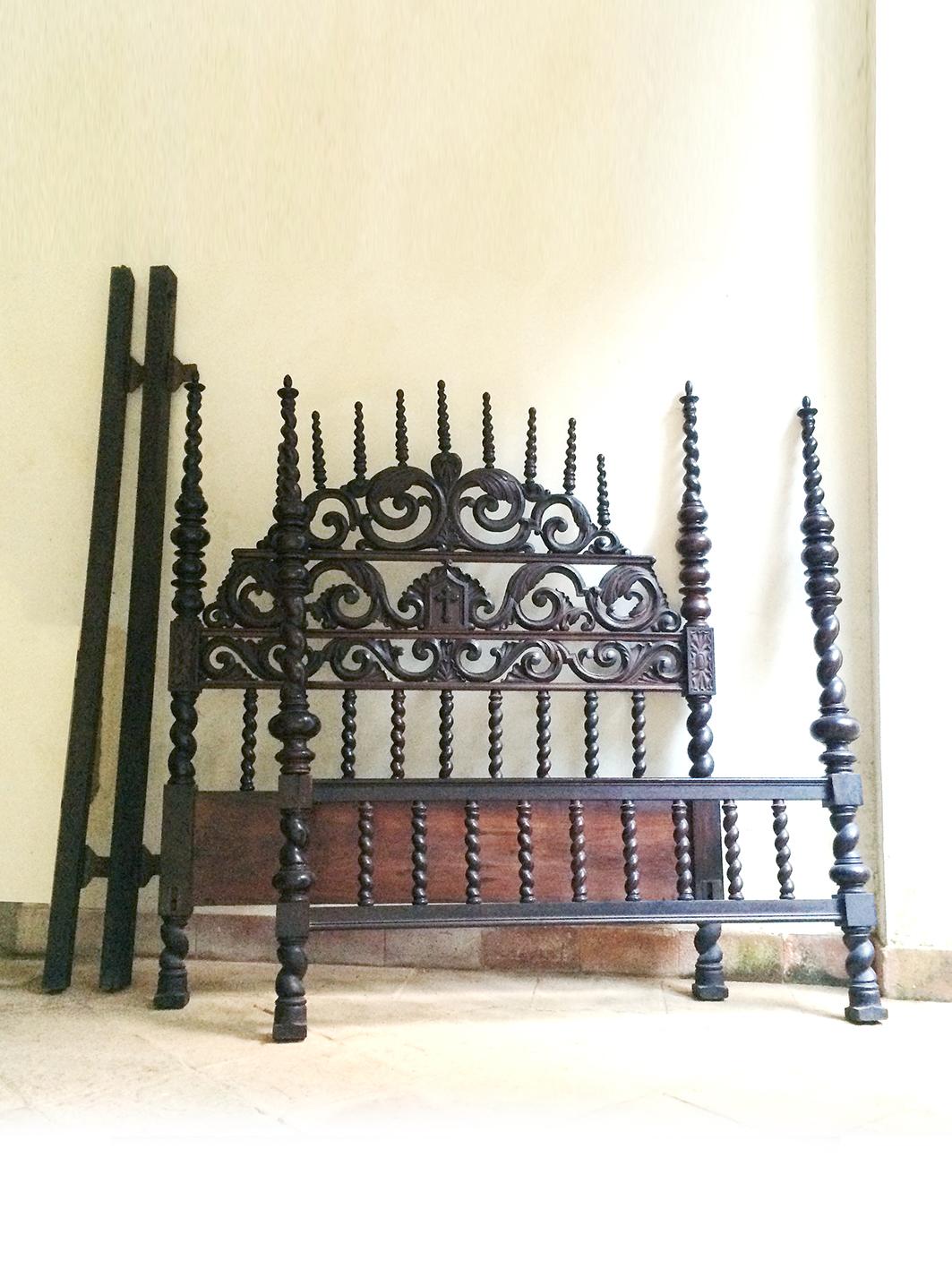 This 19th-century Spanish Colonial bed is a magnificent example of antique craftsmanship, reflecting the rich tradition of colonial furniture design. Carved in dark wood, it features intricate spindle work and detailed ornamentation, particularly in