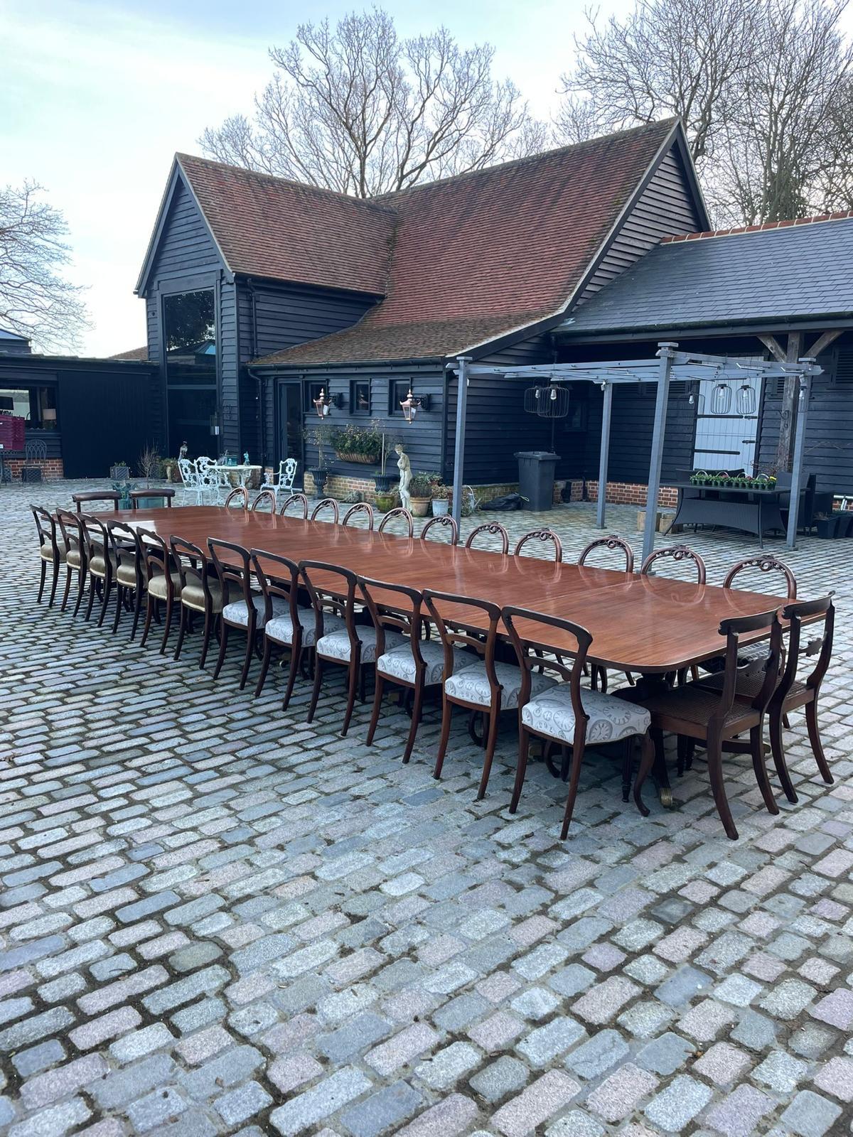 Rare 28 seater 6 pilar antique George III quality mahogany dining table having a large quality figured mahogany top supported by six turned shaped pedestal columns.  Each pedestal column stands on 4 reeded sabre legs with original brass feet and