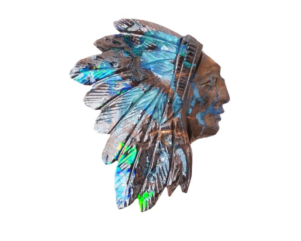 A vintage opal Indian head carving, weighing 32.10 carats, featuring an intricate piece of lapidary artistry. Crafted from opal, a gemstone known for its iridescent play of colors, the carving depicts the profile of an Indian head with intricate