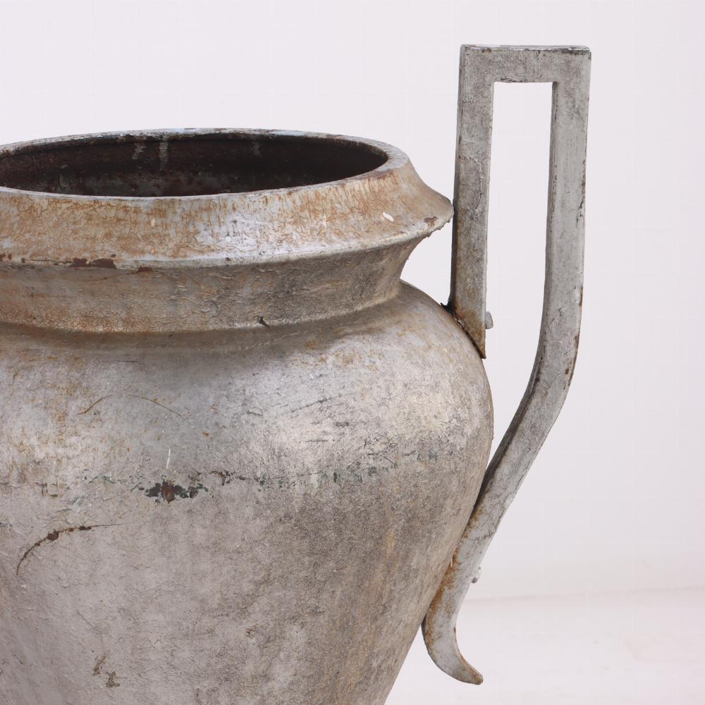 Standing an impressive 36 inches tall, each urn features classic Art Deco styling with bold, sculptural lines and elegant vasiform bodies. The double-handled design adds a sense of symmetry and grandeur, while the weathered surface patina enhances