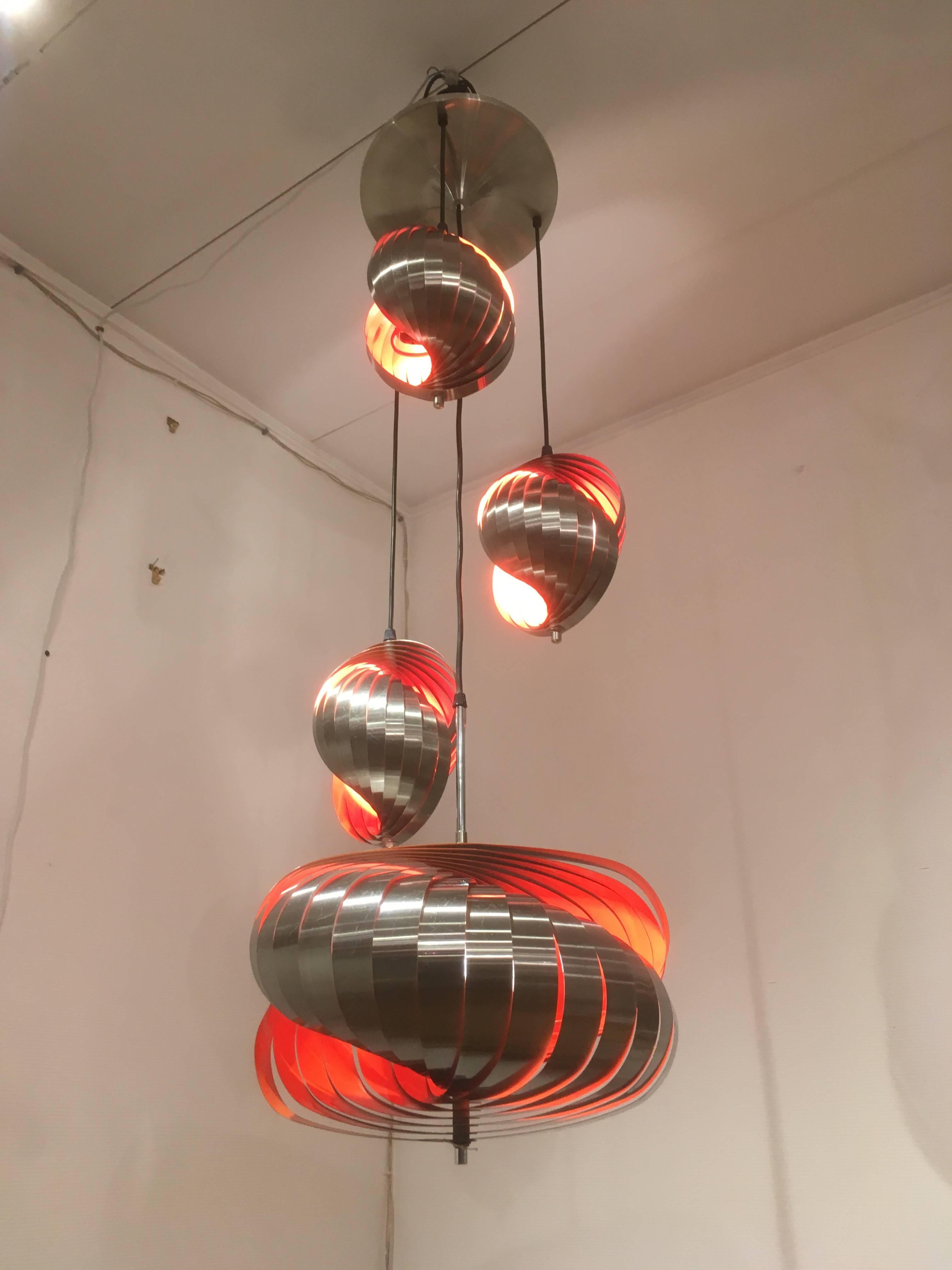 Aluminium light designed by Henri Mathieu in the 1970s.
Each pendant is made of bands of brushed metal, lacquered in orange inside radiating warm light.
The pendants could be hung at different heights.