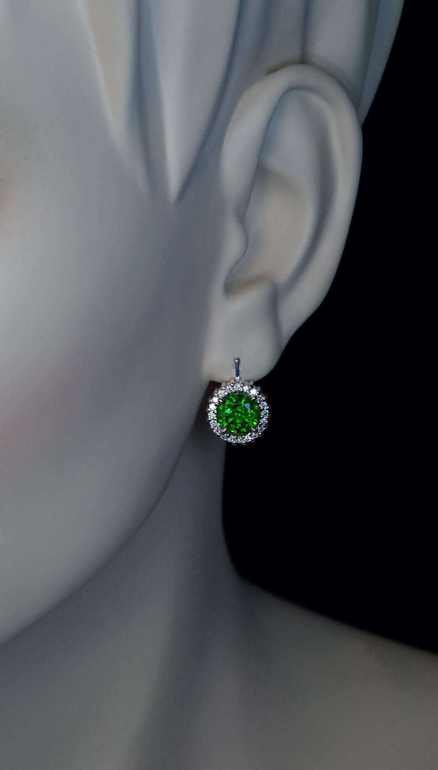 These contemporary custom-made 14K white gold earrings feature a pair of excellent Russian demantoids (2.23 ct and 2.24 ct) of deep pure green color. The center stones are encircled by bright white diamonds (F-G color, VS2-SI1 clarity).

Demantoids