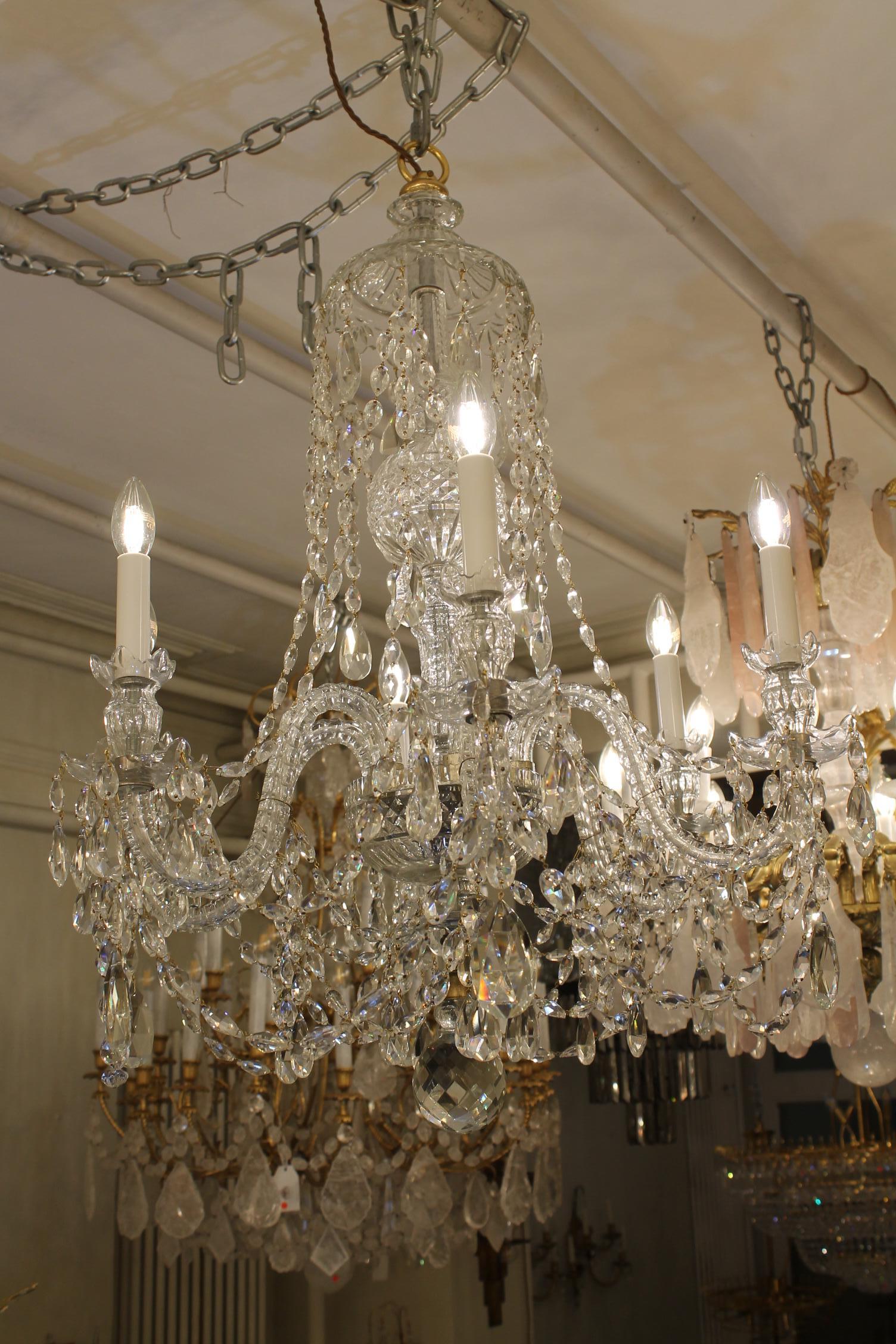 The receiver plate supports six candle arms each ending with slip over drop hung drip pans.  The baluster stem rises up to crystal ball and then upwards an upturned crystal dish from which English crystal buttons festoon out to the 6 arms.  Below