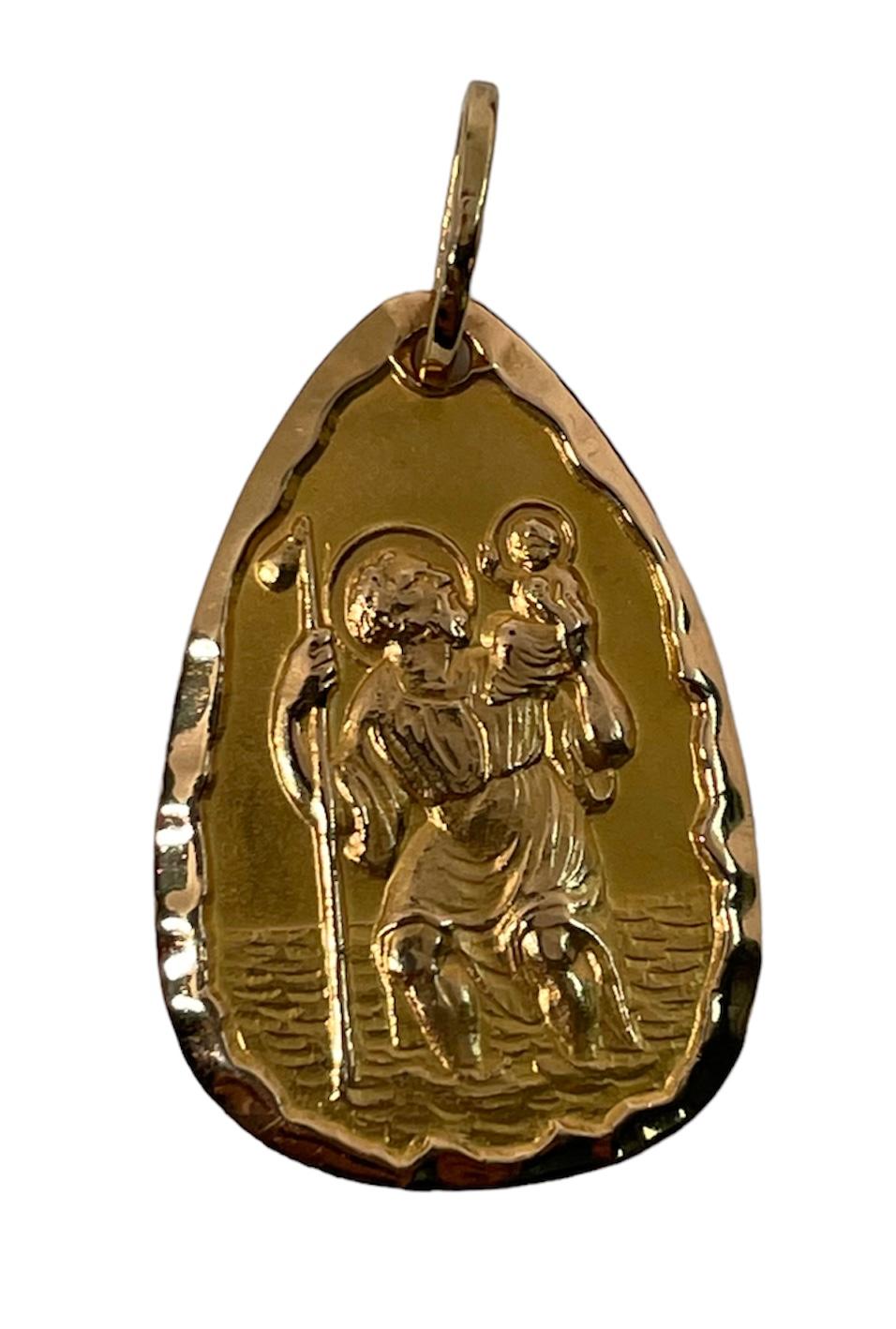 This is a rare 750 (18k) yellow gold religious medal pendant of Saint Christopher. It is pear shaped solid gold and depicts a very well done hand carving of St.Christopher who is carrying Baby Jesus with one hand and with the other one, his staff,